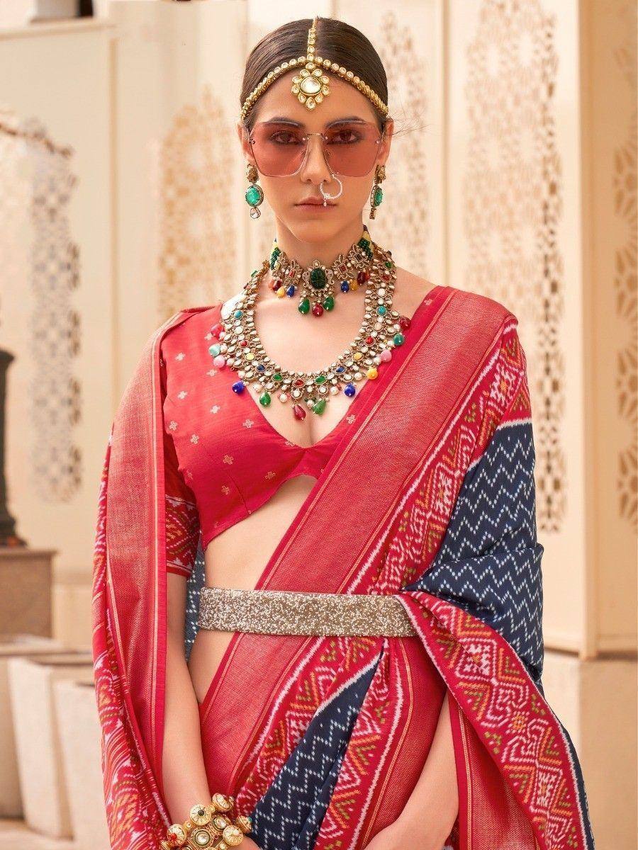 Red and navy blue ethnic saree with geometric print, paired with statement jewelry and a cutout blouse
