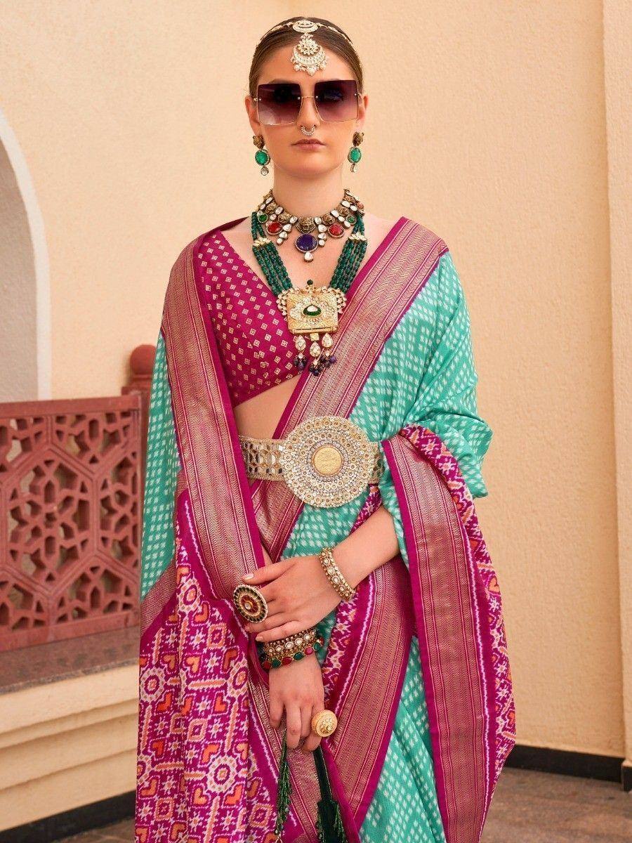 Elegant Indian saree with pink and green patterns, paired with traditional jewelry and sunglasses.