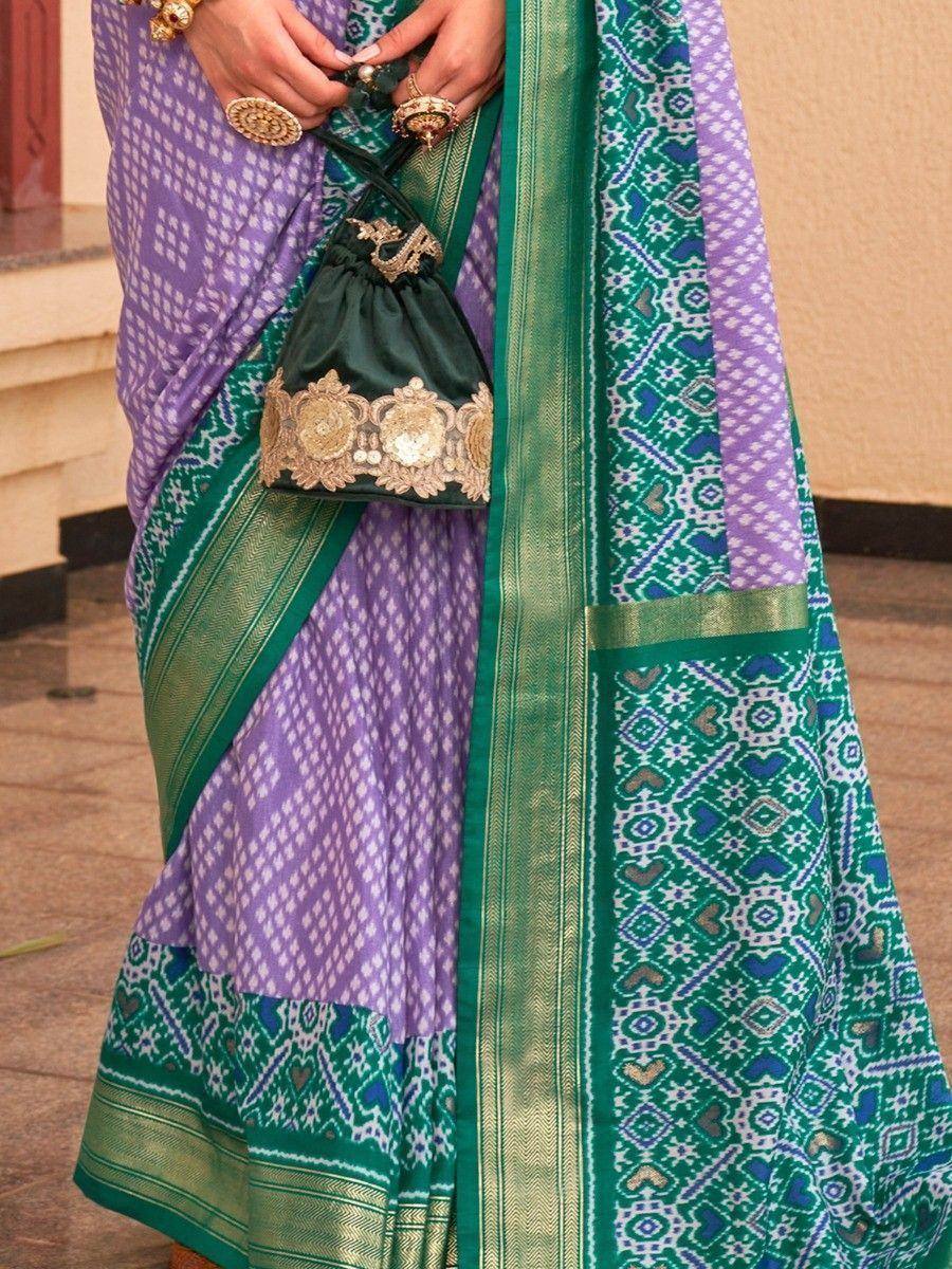 Purple and green ethnic saree with intricate patterns and golden embroidery, paired with a matching potli bag.