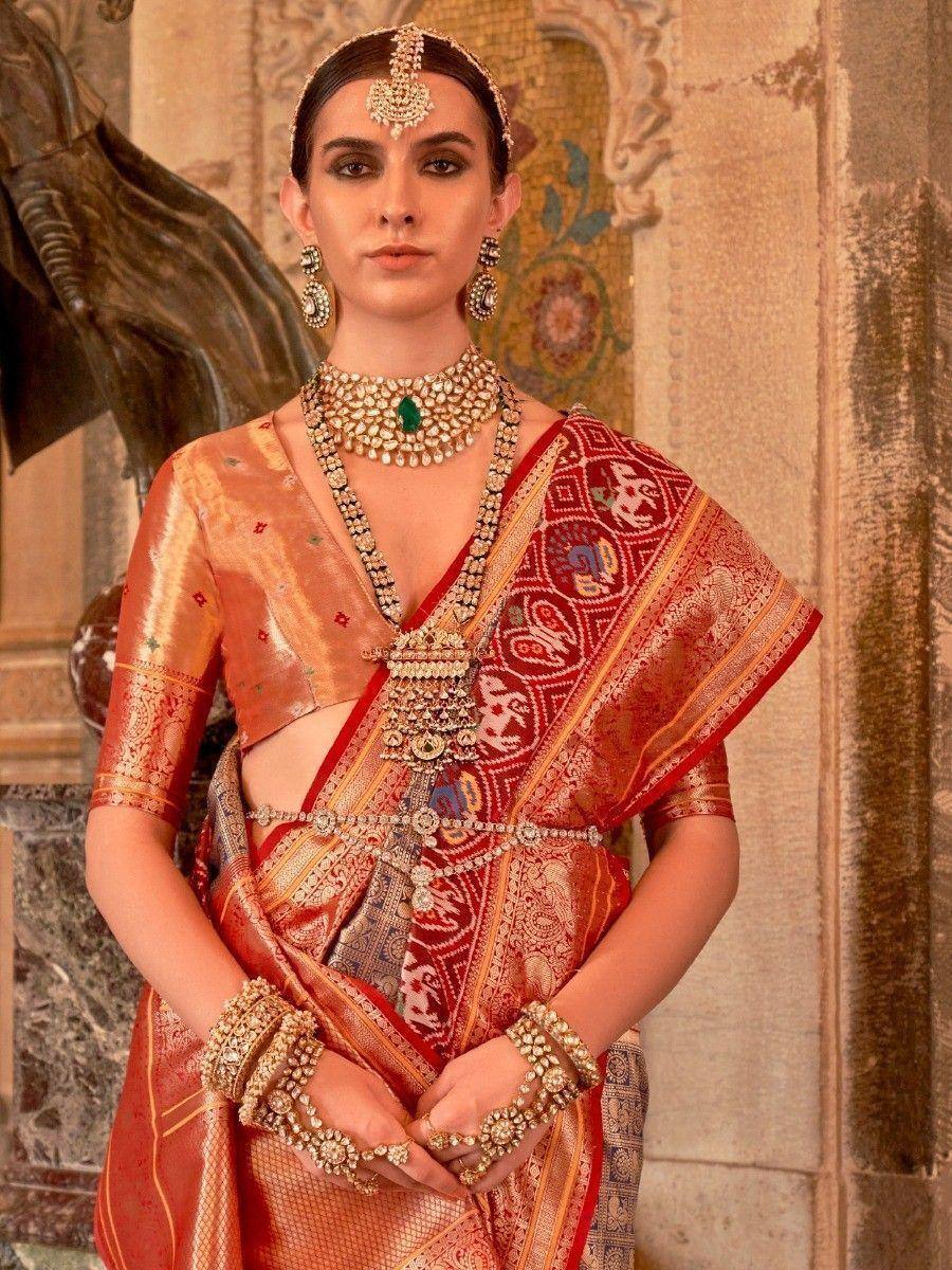 Woman in red and gold designer saree with heavy jewelry, traditional Indian ethnic wear