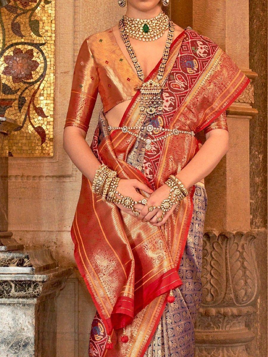 Red and gold designer saree with intricate patterns, paired with traditional Indian jewelry for festive occasions