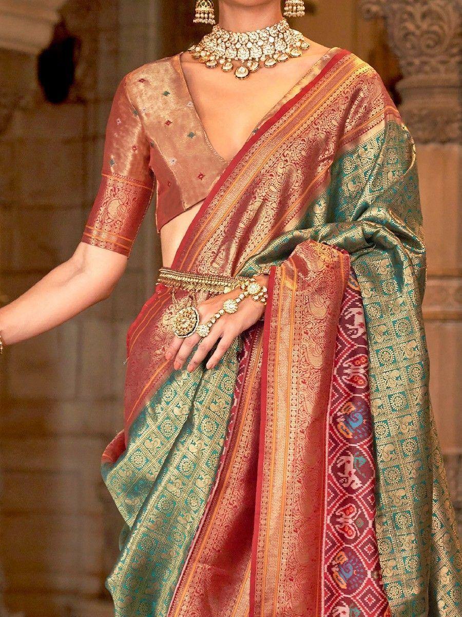 Elegant Indian saree with intricate gold embroidery and vibrant red-green hues, paired with traditional jewelry.