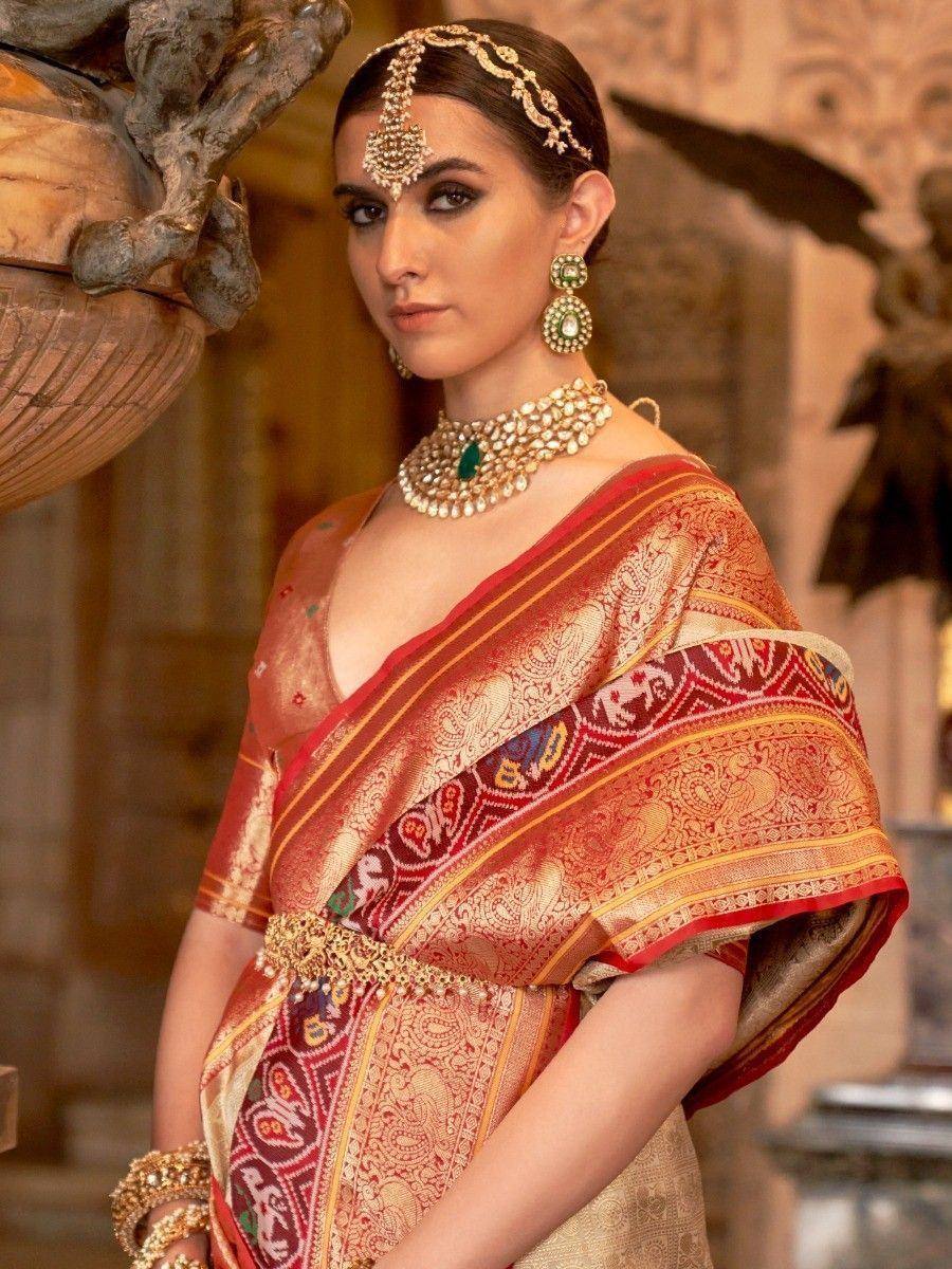 Woman in red and gold embroidered saree with traditional Indian jewelry, perfect for ethnic occasions.
