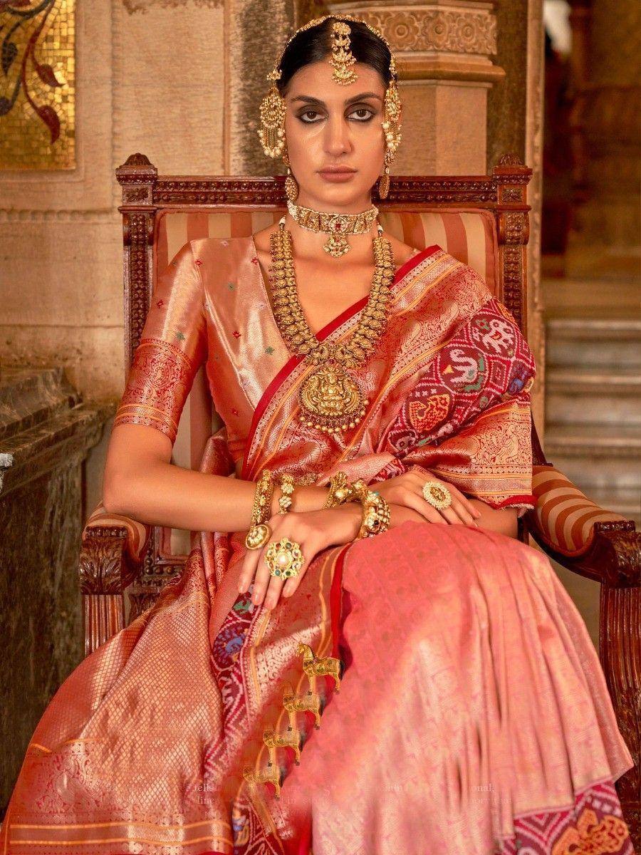 Elegant woman in traditional Indian saree with gold jewelry, seated on ornate chair