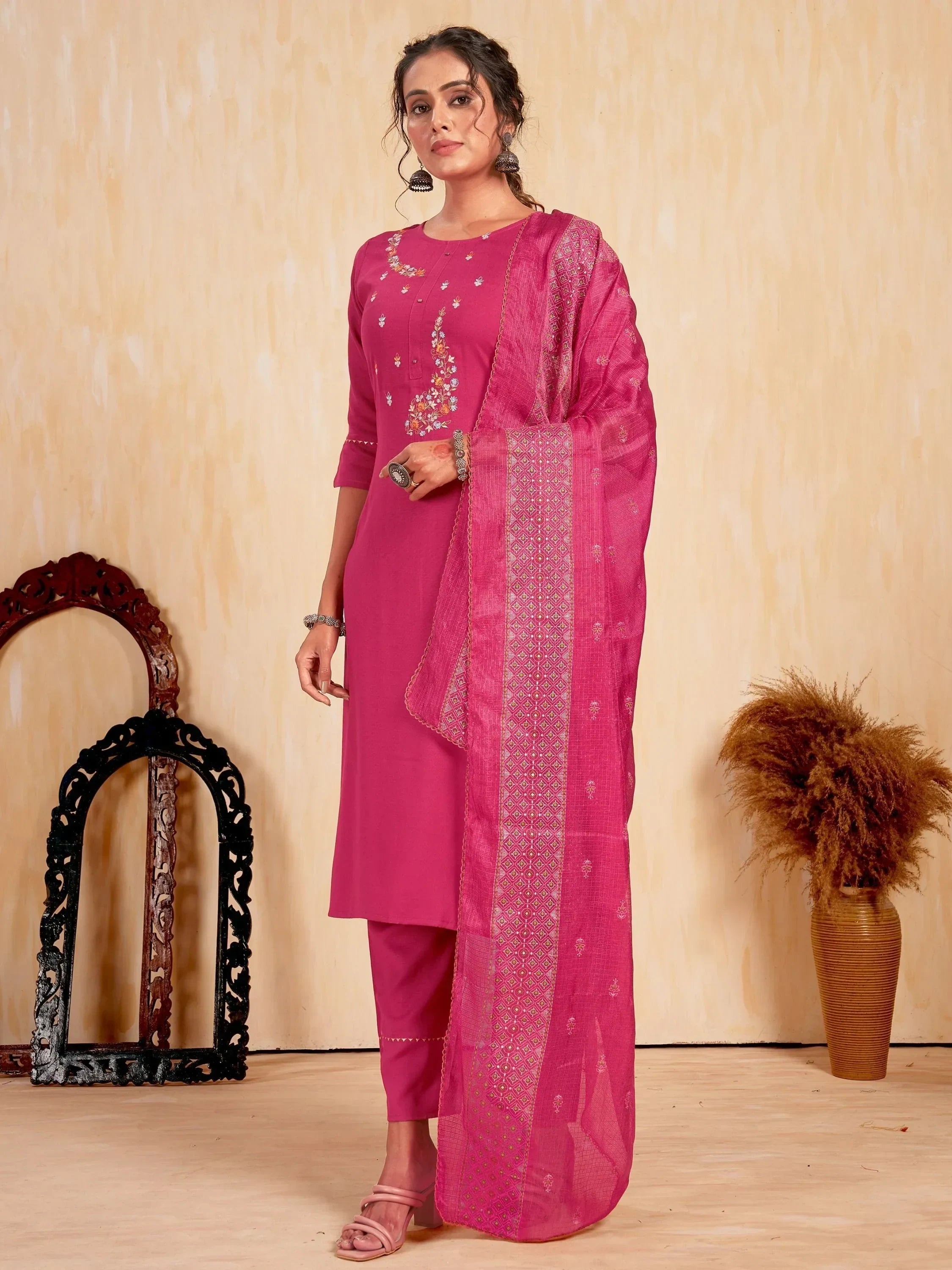 Woman wearing pink embroidered salwar kameez with matching dupatta and traditional jewelry