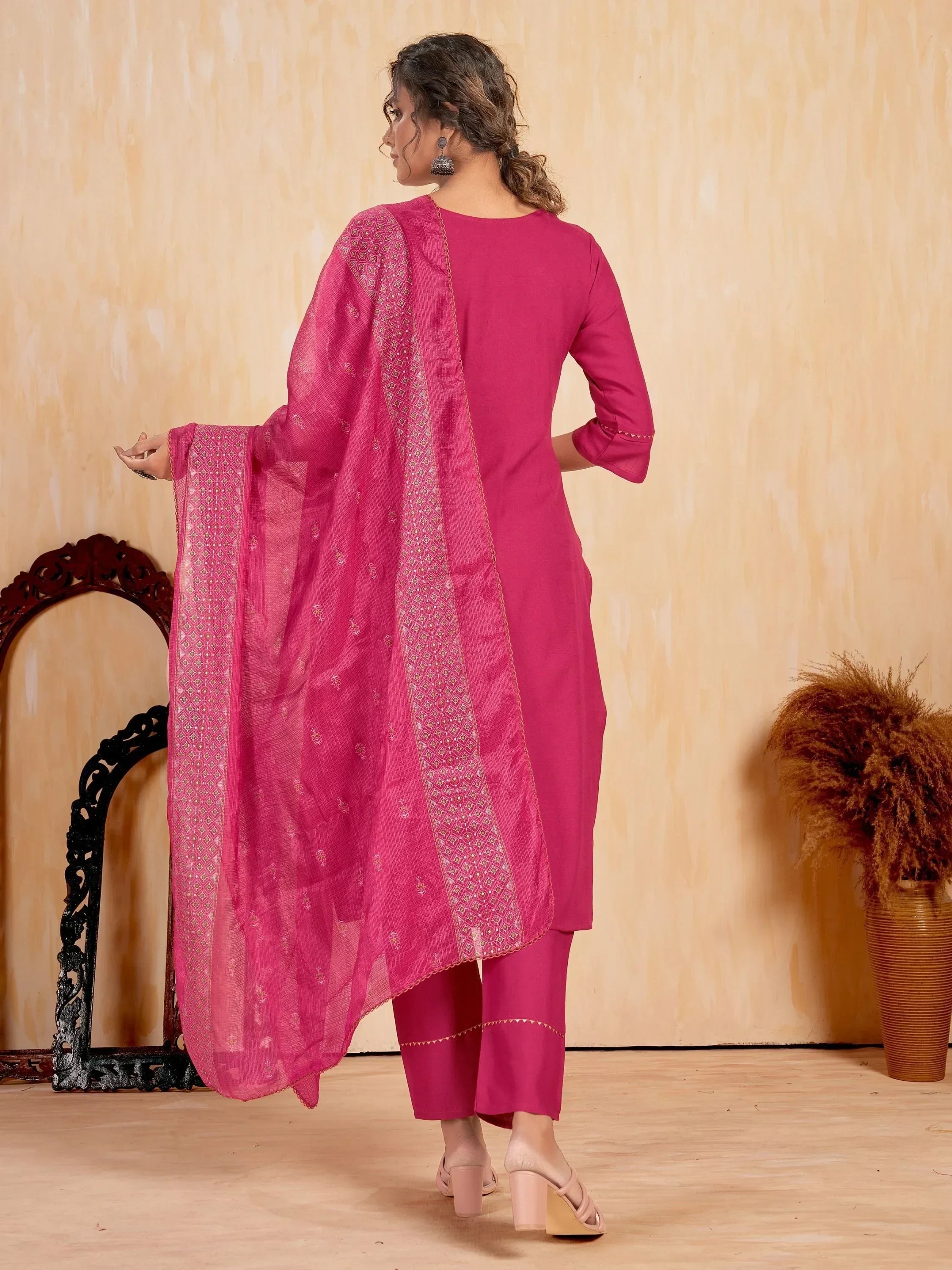 Woman in pink salwar kameez with embroidered dupatta and heels, back view
