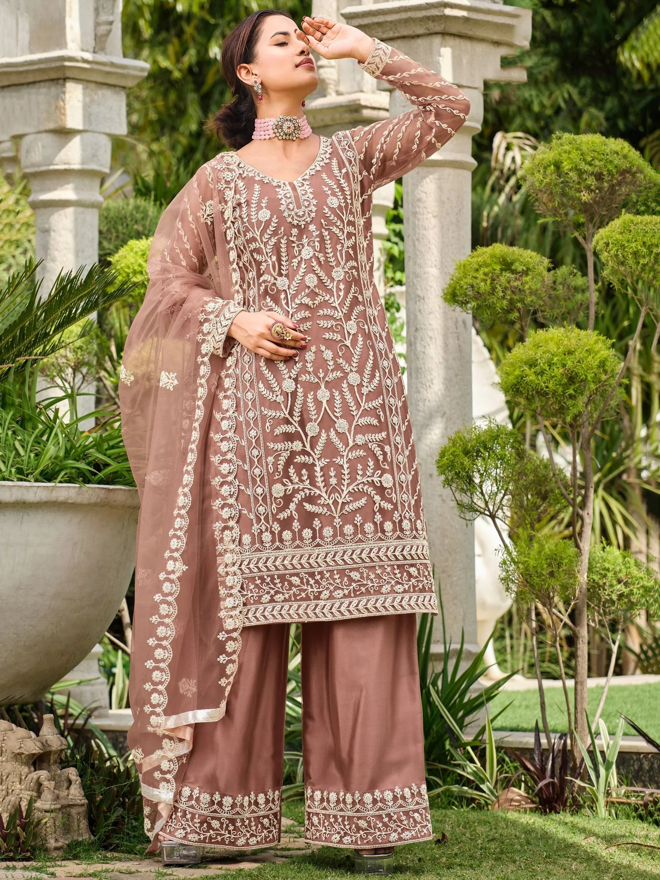 Woman wearing embroidered mauve salwar kameez with dupatta in a garden setting