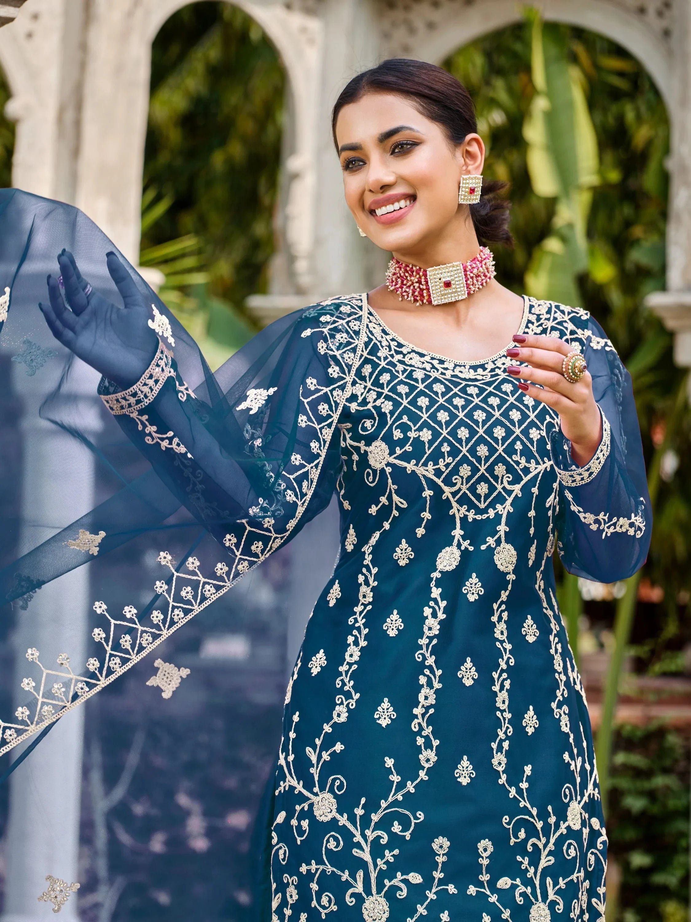 Woman in navy blue embroidered Indian salwar kameez with net dupatta, outdoor setting