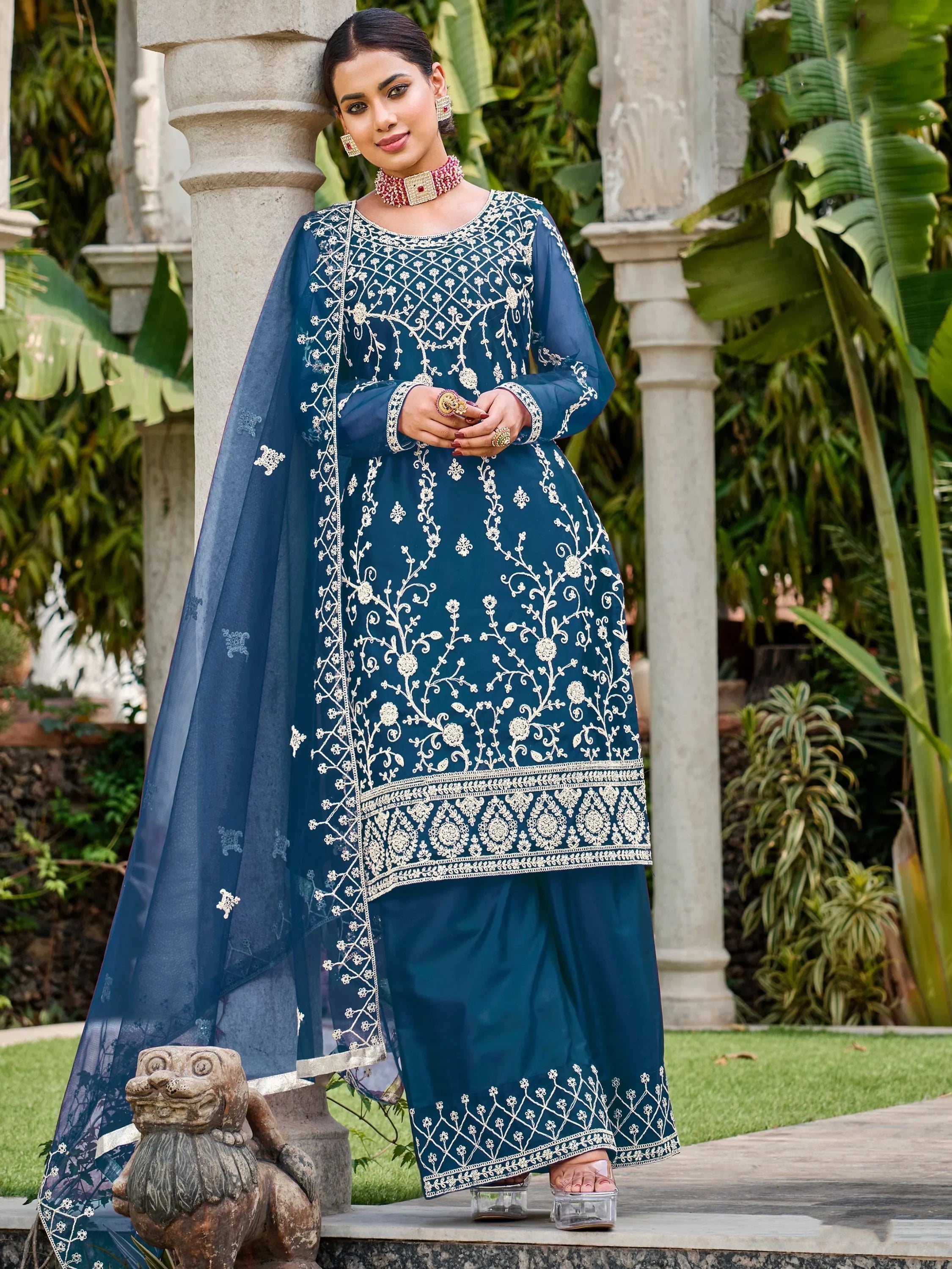 Woman wearing navy blue embroidered salwar kameez with dupatta, standing outdoors