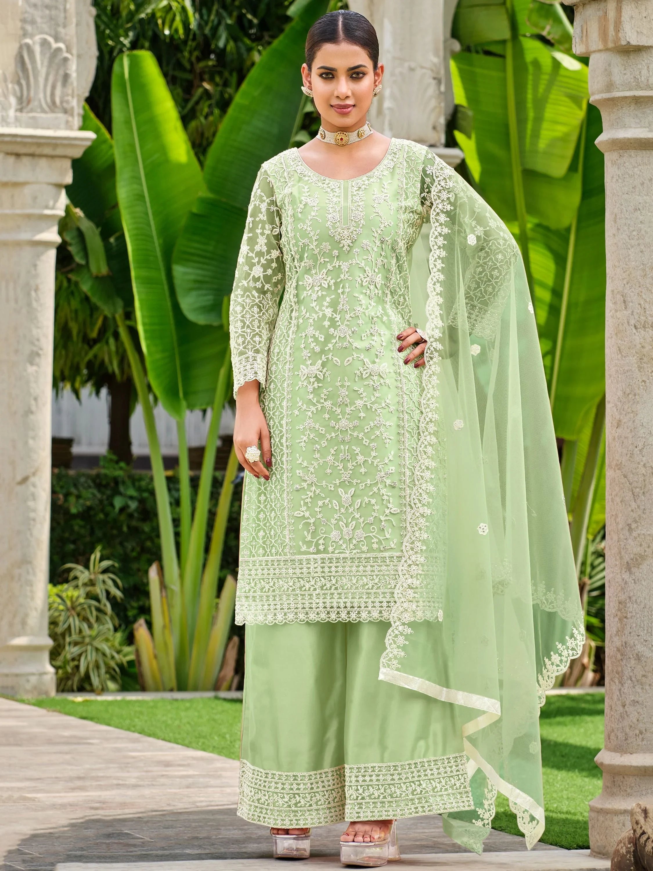 Woman wearing pastel green embroidered salwar kameez with matching dupatta outdoors