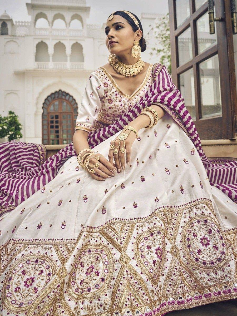 White and purple embroidered lehenga choli with gold jewelry, perfect for Indian weddings and festive occasions.