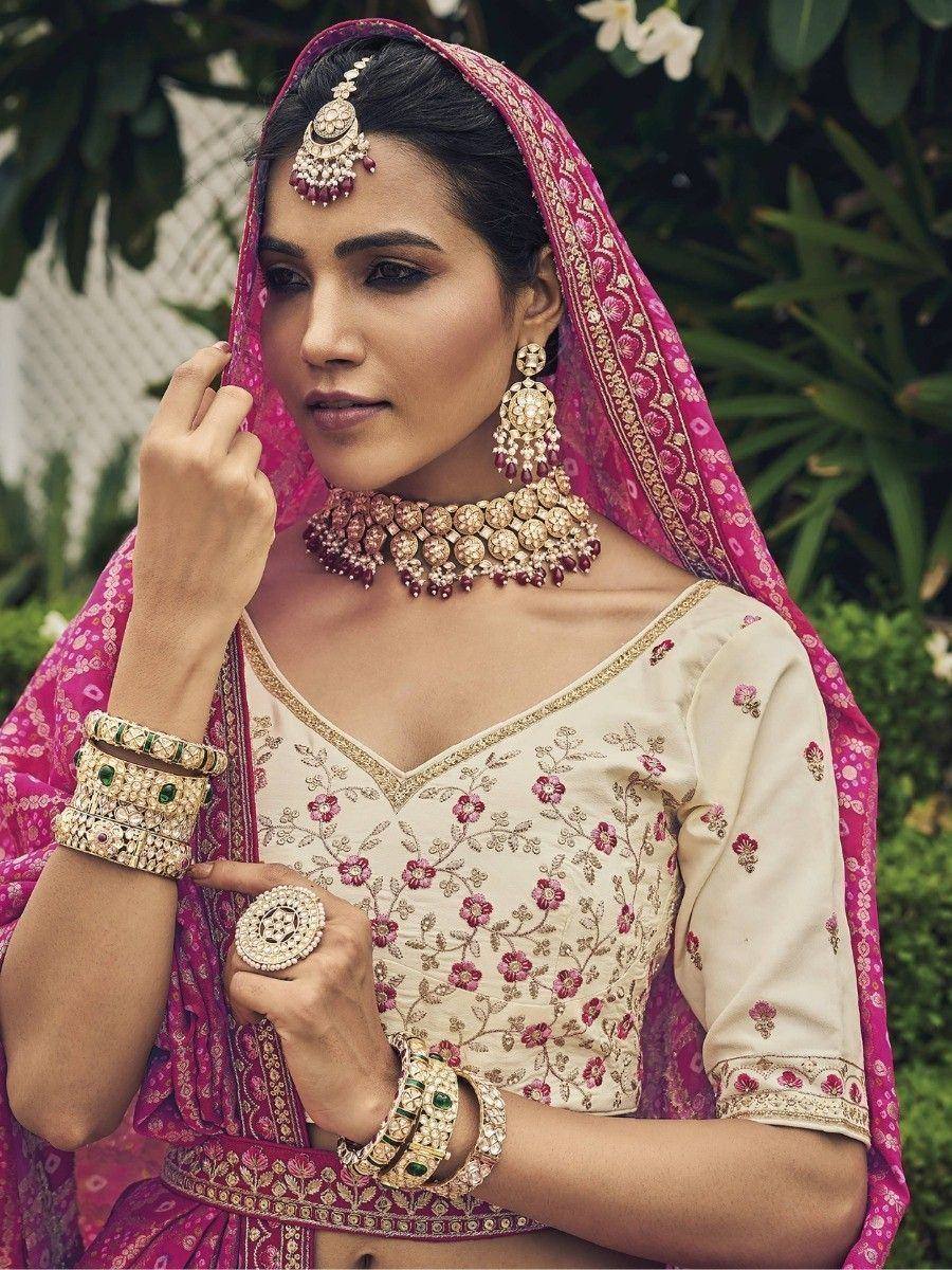 Elegant Indian bridal lehenga choli with floral embroidery, pink dupatta, and traditional jewelry