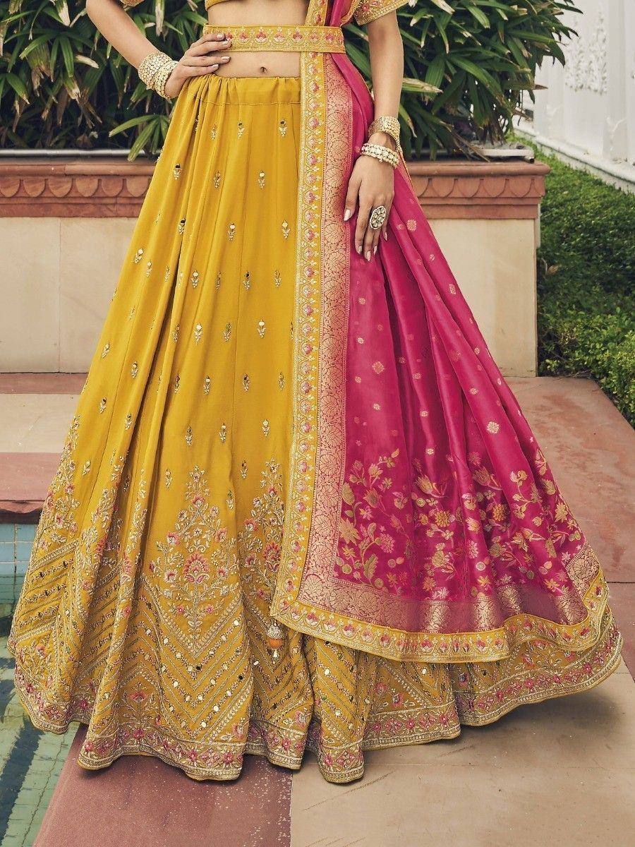 Yellow and pink designer lehenga choli with intricate embroidery and floral dupatta, perfect for Indian weddings.