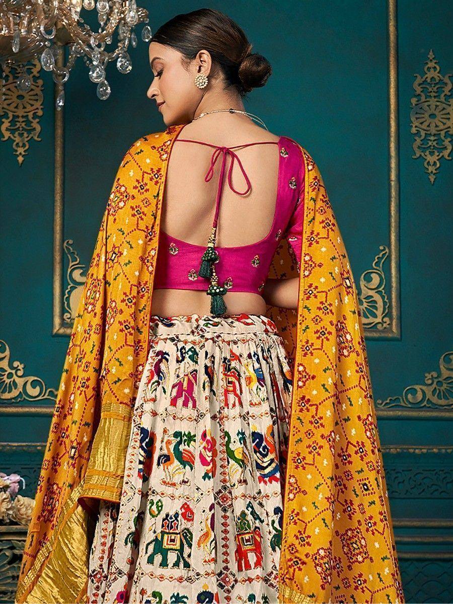 Pink backless blouse with tassels, colorful embroidered lehenga, and yellow dupatta for Indian ethnic wear