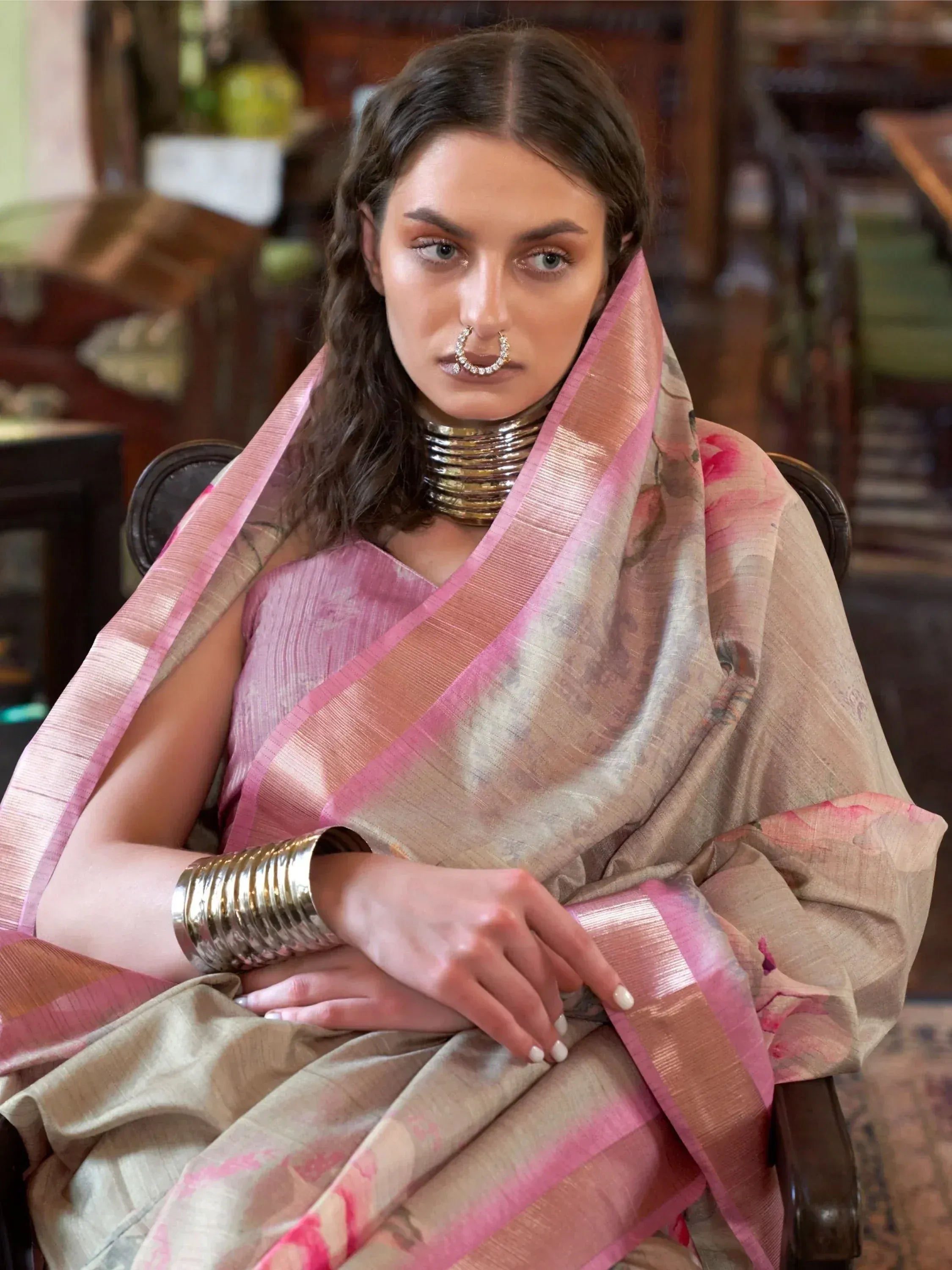 Woman in elegant pink and beige floral saree with traditional gold jewelry, showcasing Indian ethnic wear.