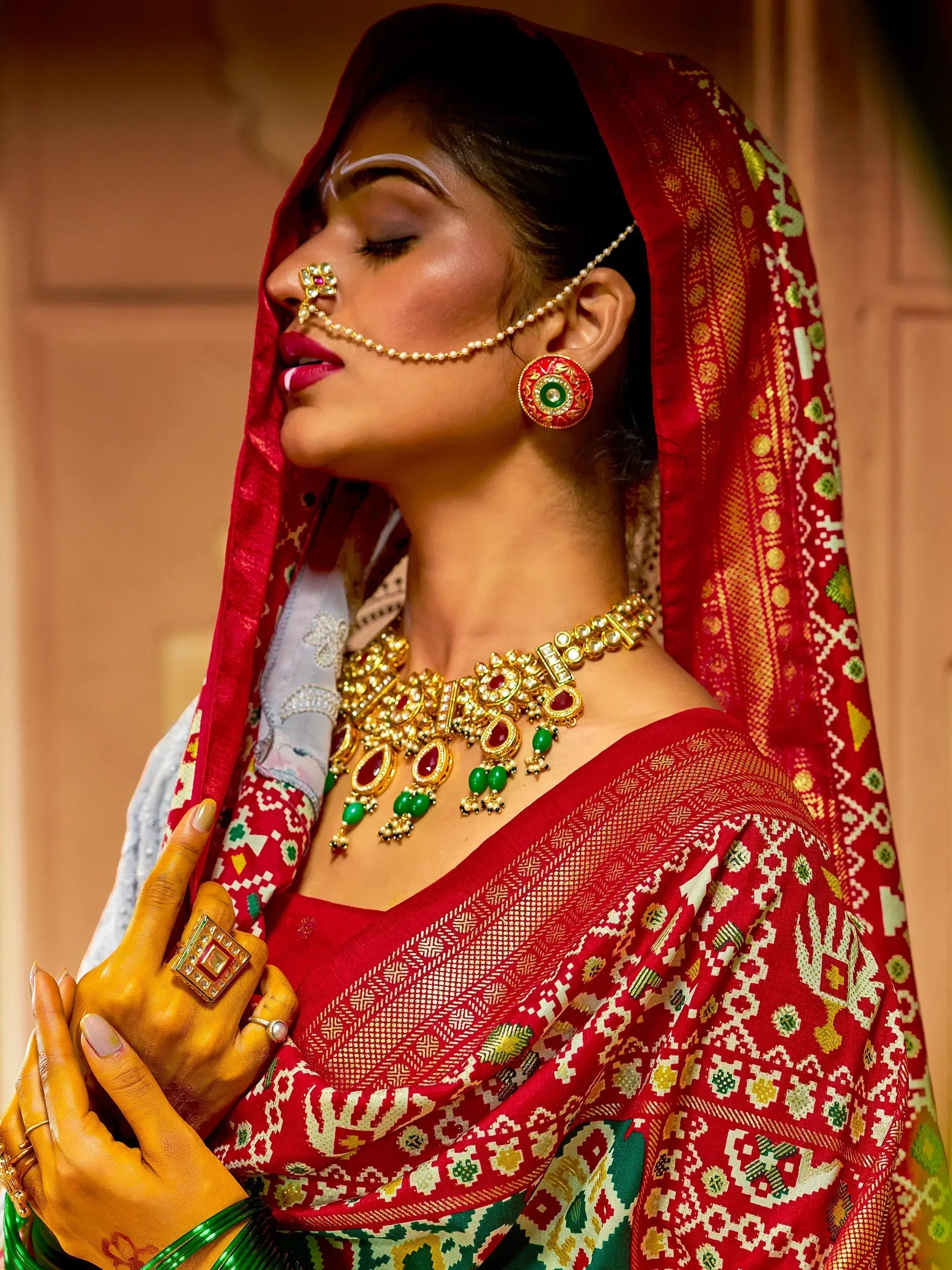 Indian bride in red ethnic saree with gold jewelry and traditional nose ring