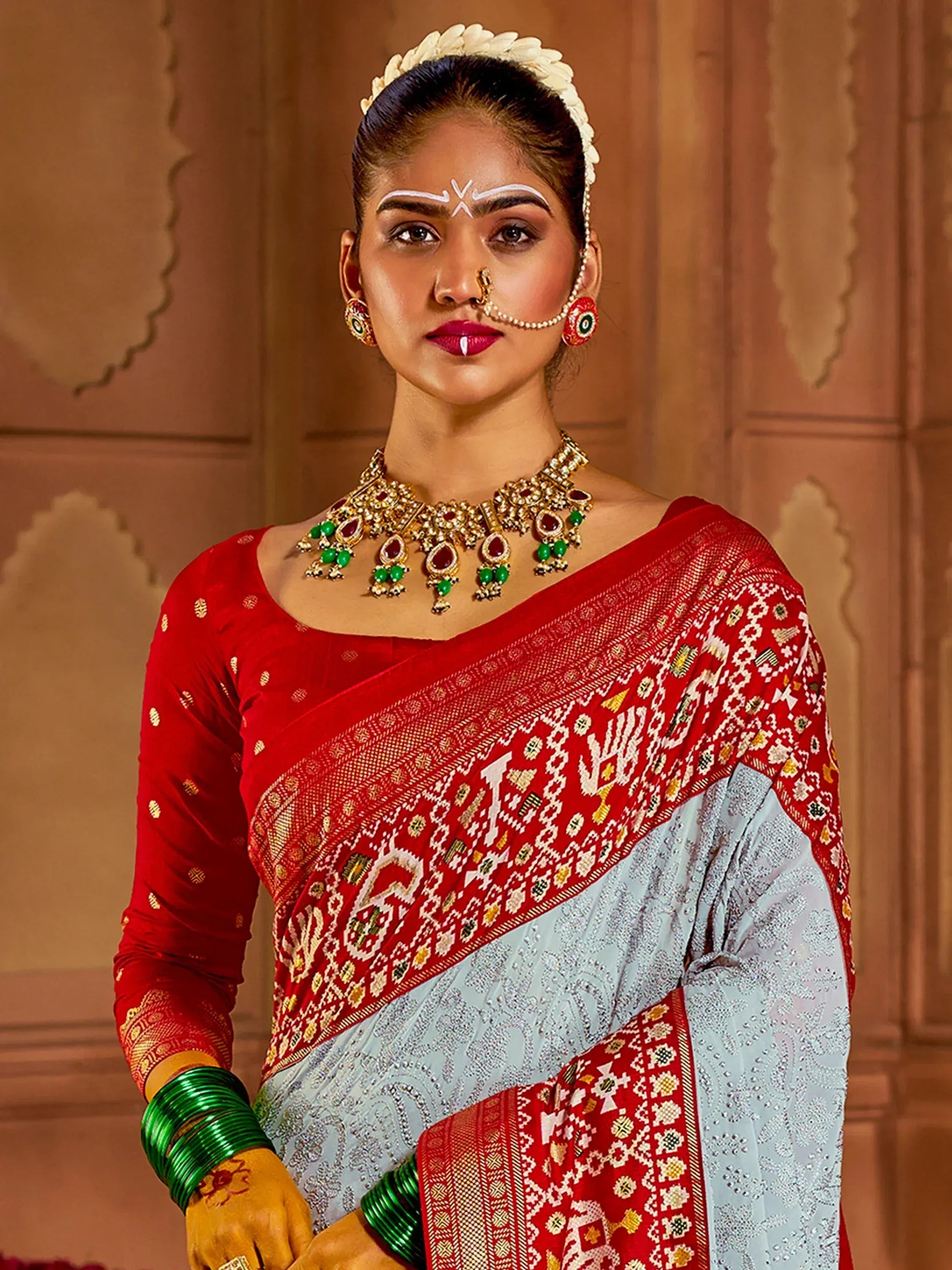 Woman in red and blue ethnic saree with gold jewelry and traditional makeup