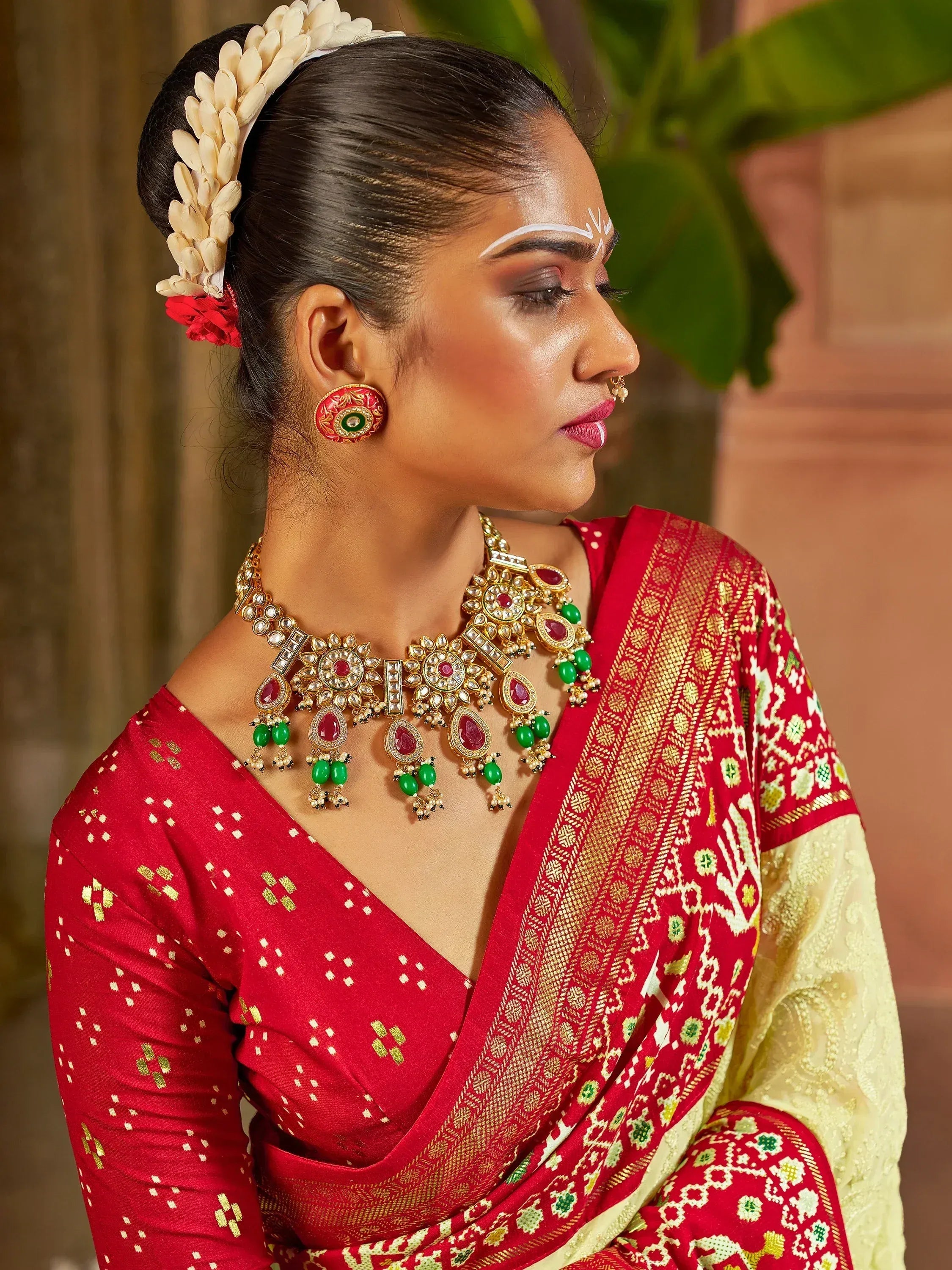 Woman in red ethnic saree with gold jewelry and floral hair accessory