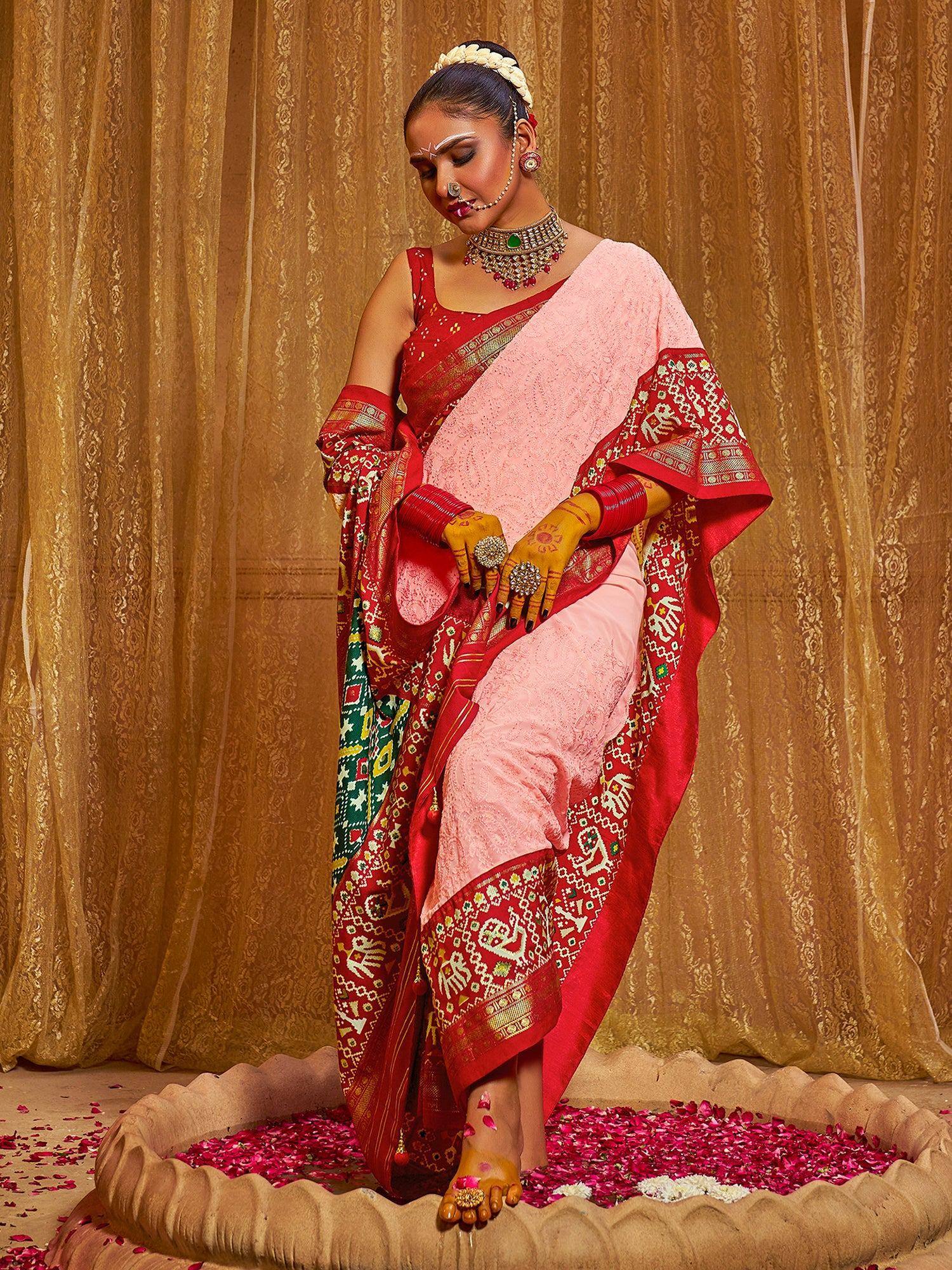 Woman in red and pink ethnic saree with elephant print, traditional jewelry, henna hands, standing on rose petals
