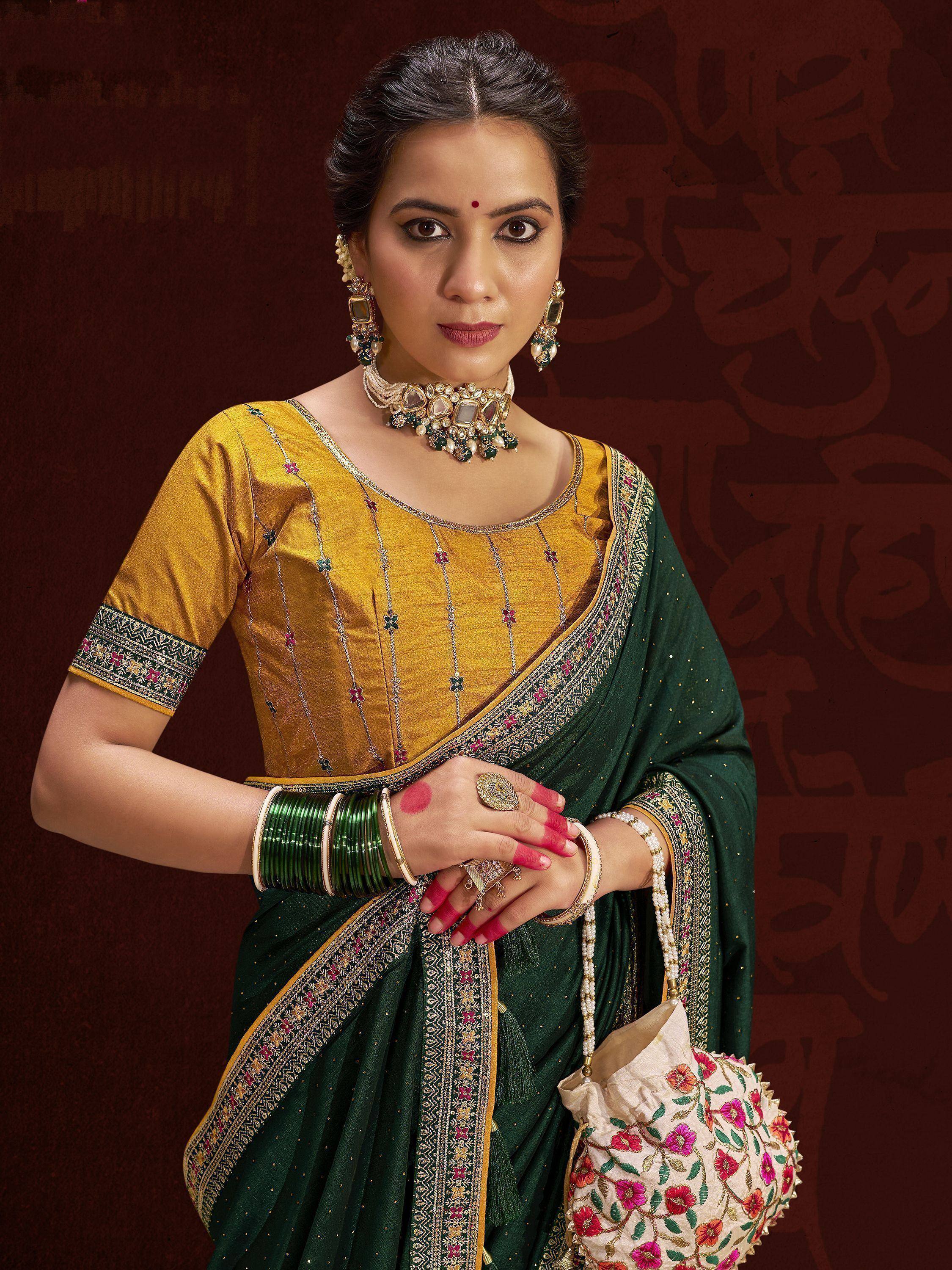 Woman in green and gold embroidered saree with traditional jewelry and floral potli bag