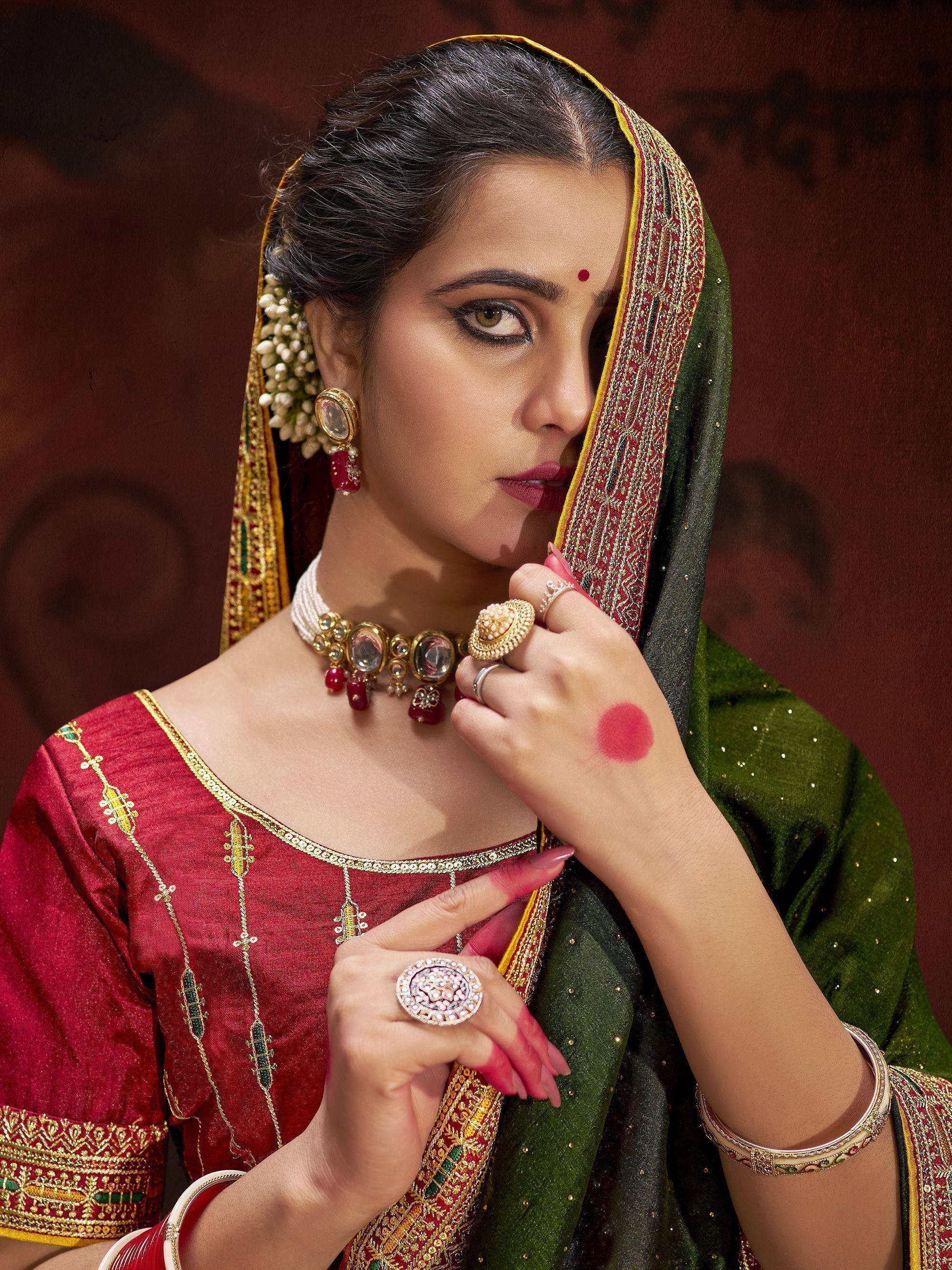 Elegant woman in red and green Indian ethnic wear with gold jewelry and floral hair accessory