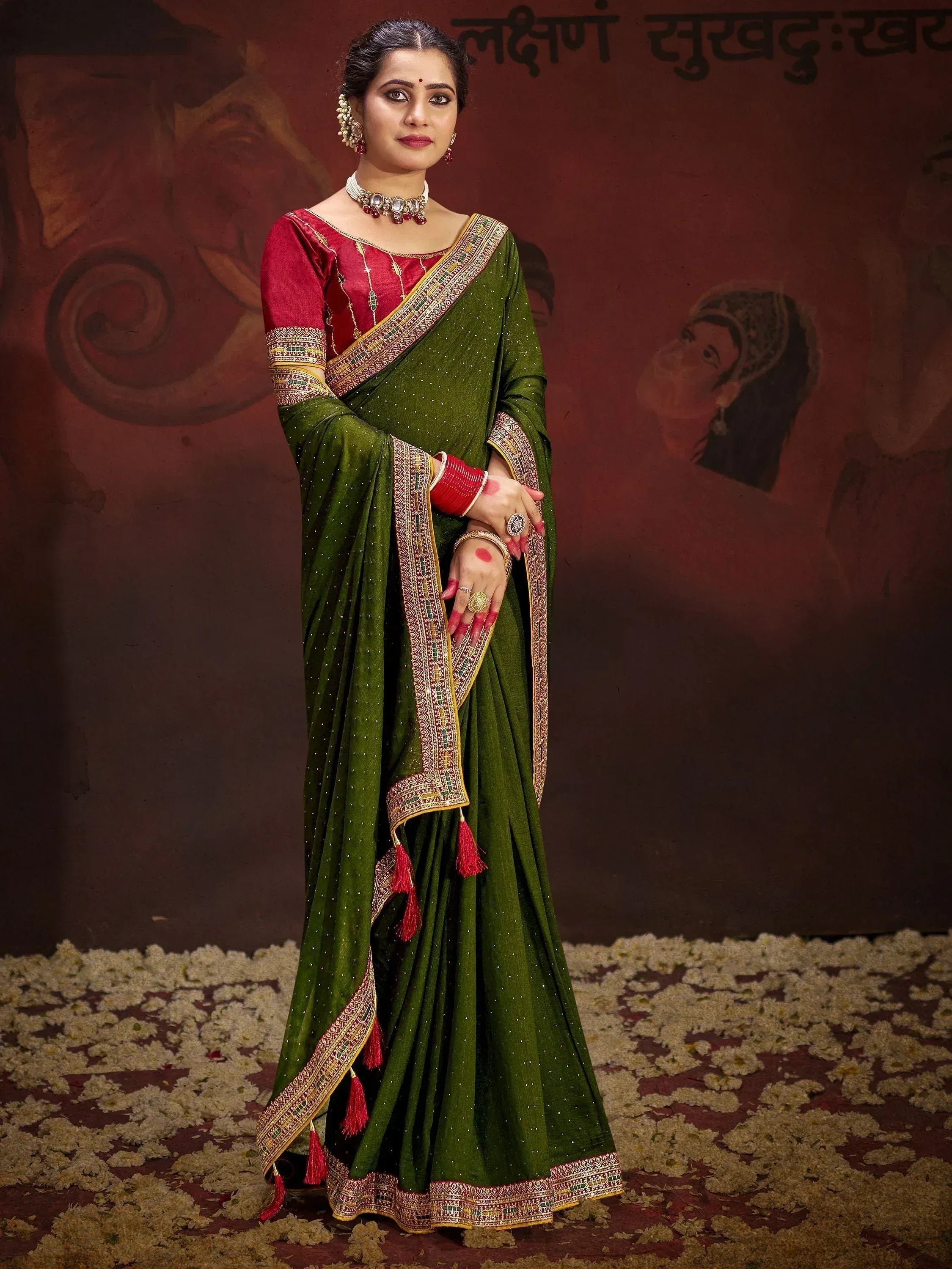 Green and red designer saree with intricate embroidery and tassels, perfect for ethnic occasions.