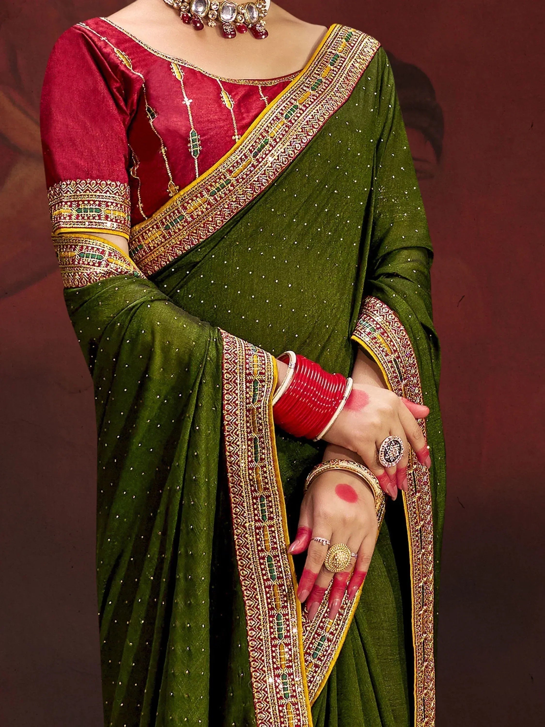 Green saree with red blouse, intricate gold embroidery, and traditional Indian jewelry for festive occasions.