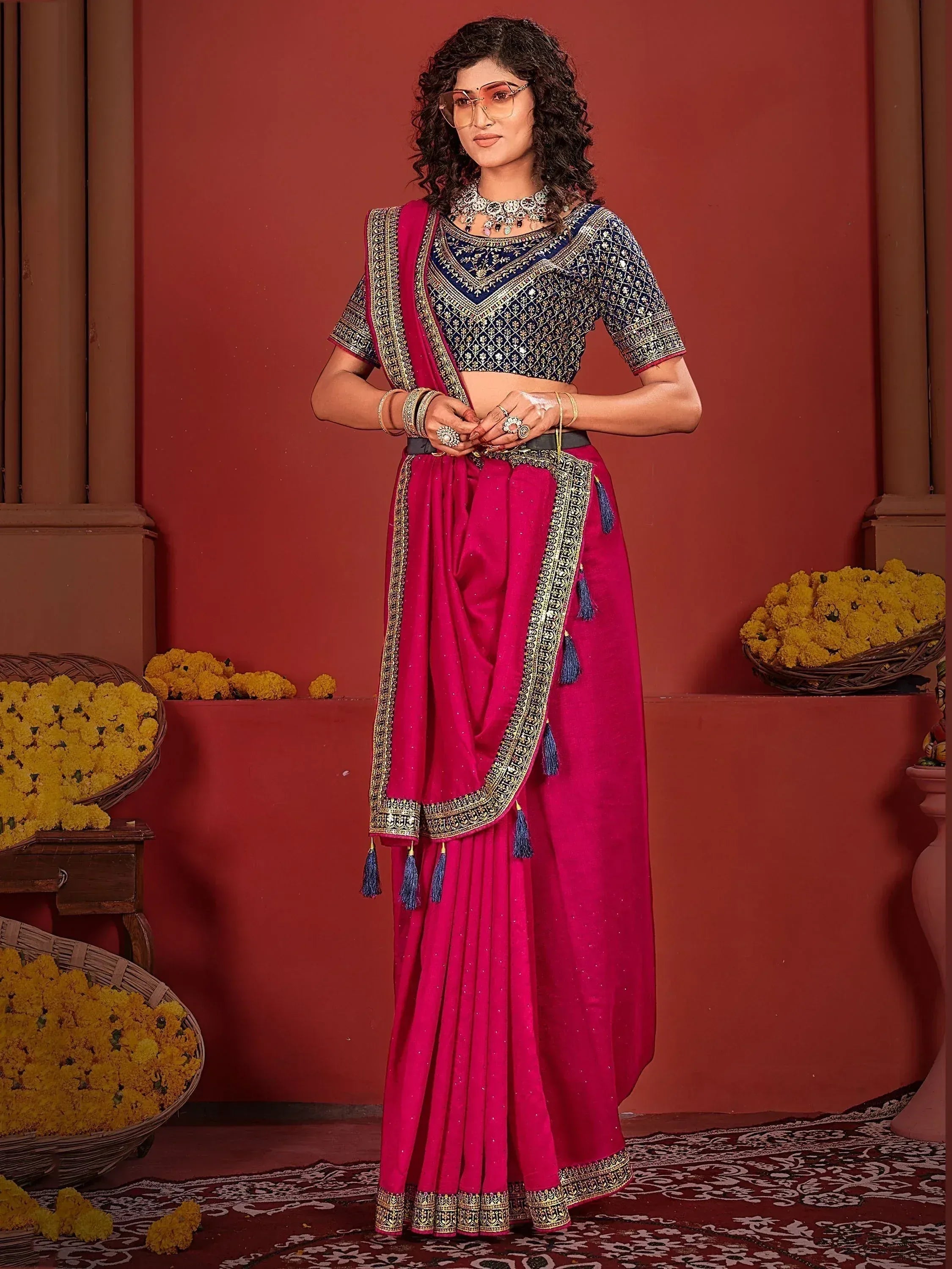 Pink and navy blue embroidered lehenga choli with gold border and tassels, styled with traditional jewelry