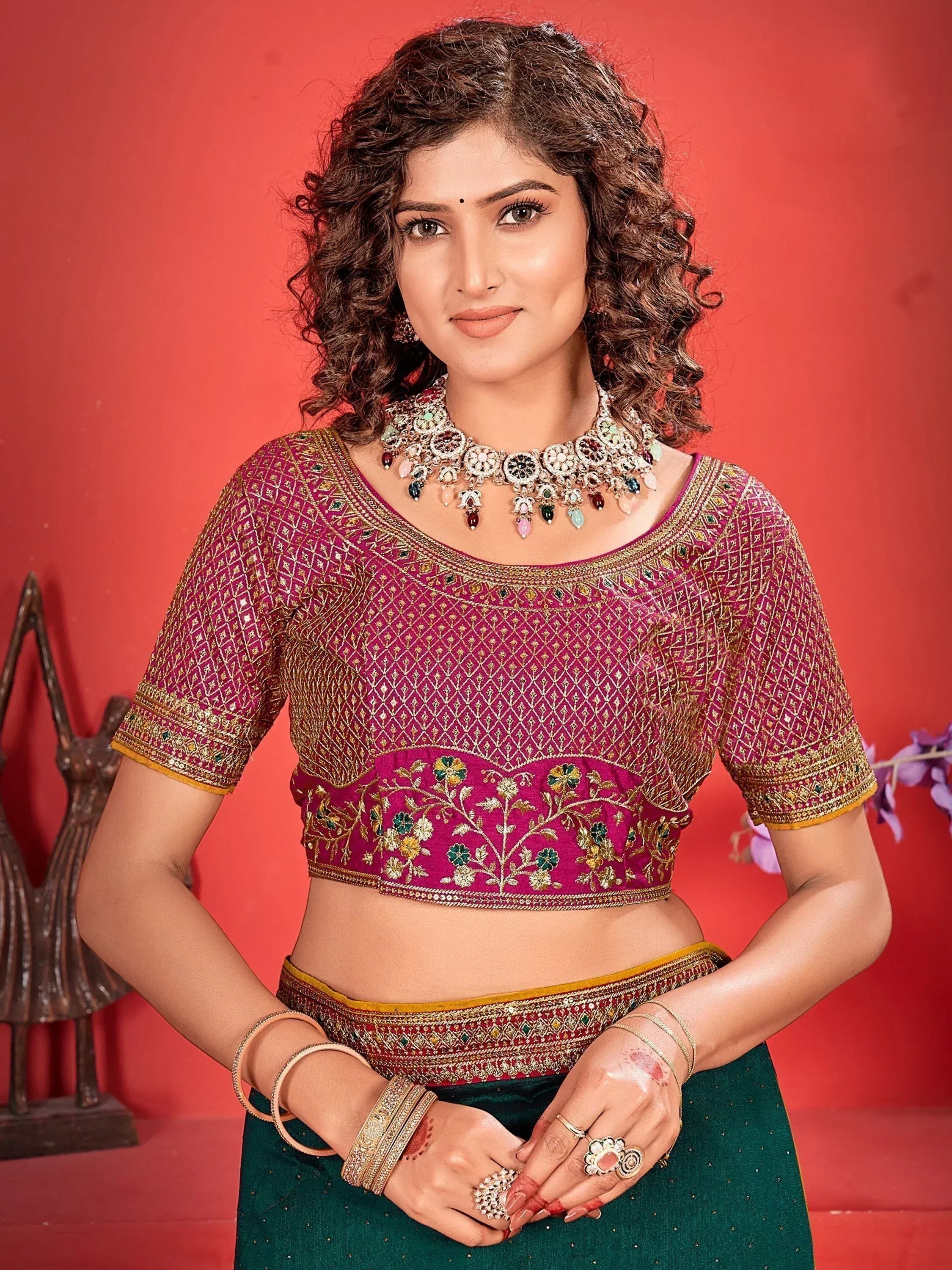 Woman in pink embroidered blouse with floral design, paired with green lehenga, traditional Indian ethnic wear