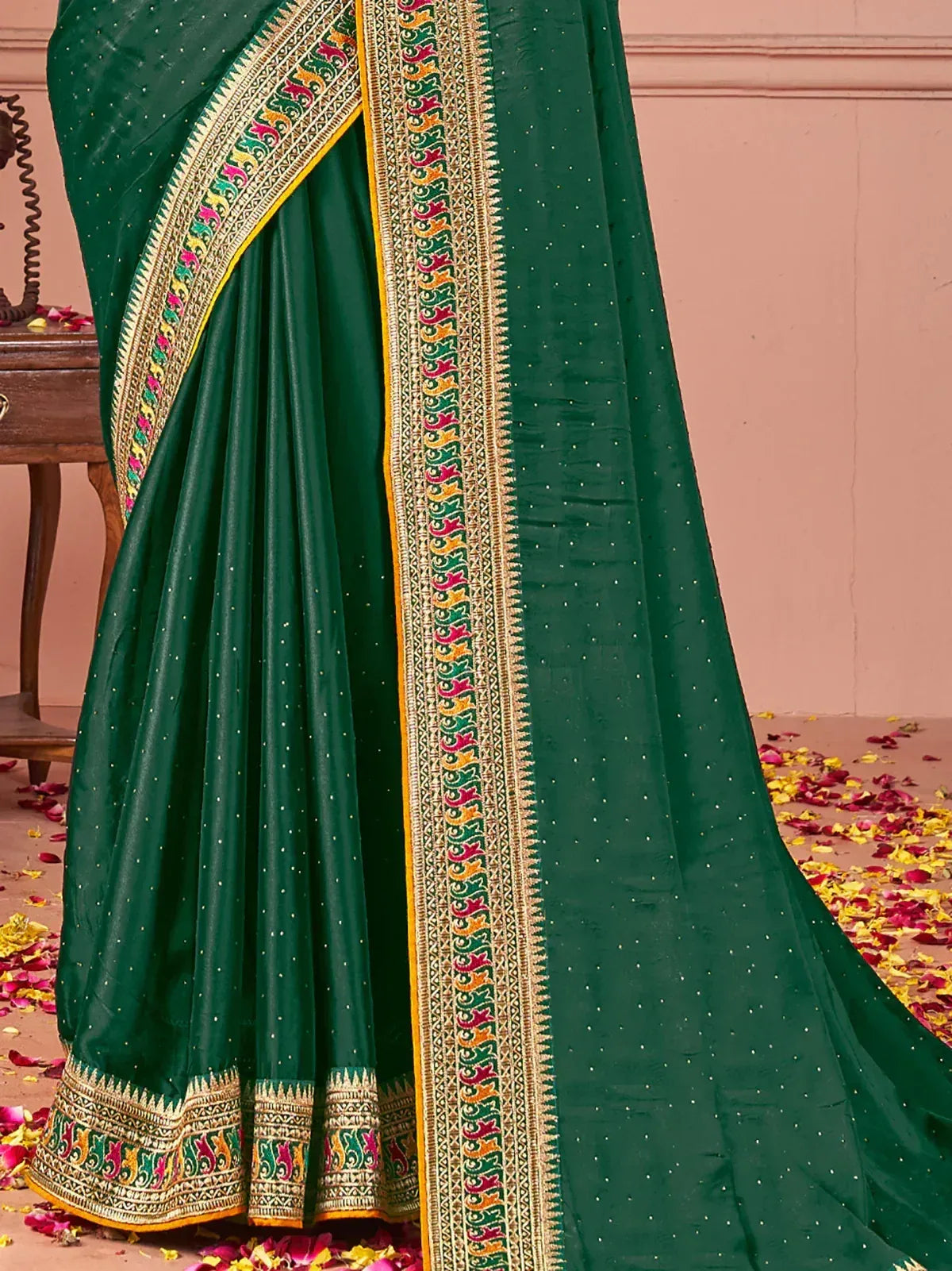 Emerald green saree with colorful embroidered border and floral motifs, perfect for ethnic occasions.