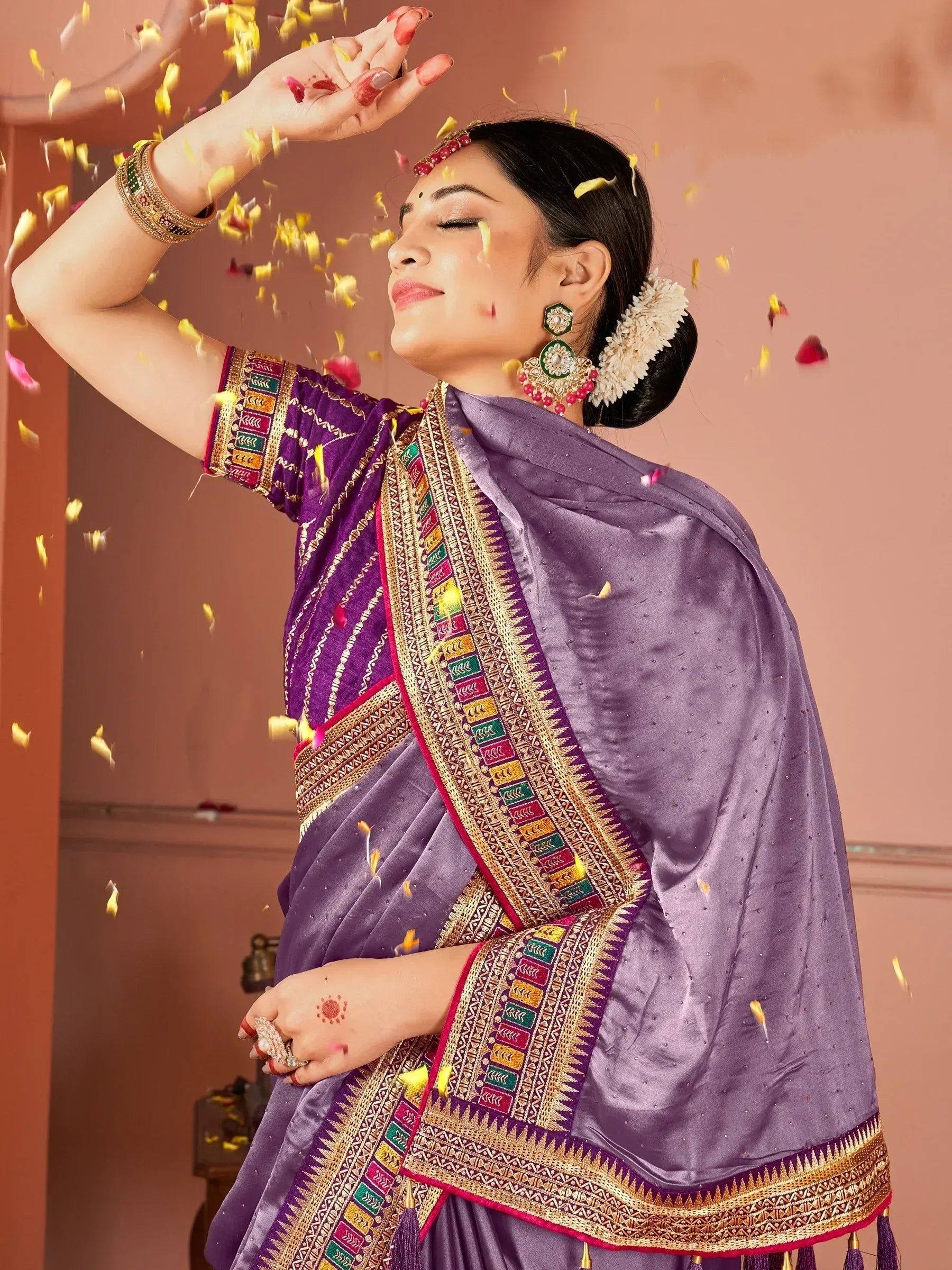 Woman in purple designer saree with gold embroidery, floral petals falling, festive Indian ethnic wear