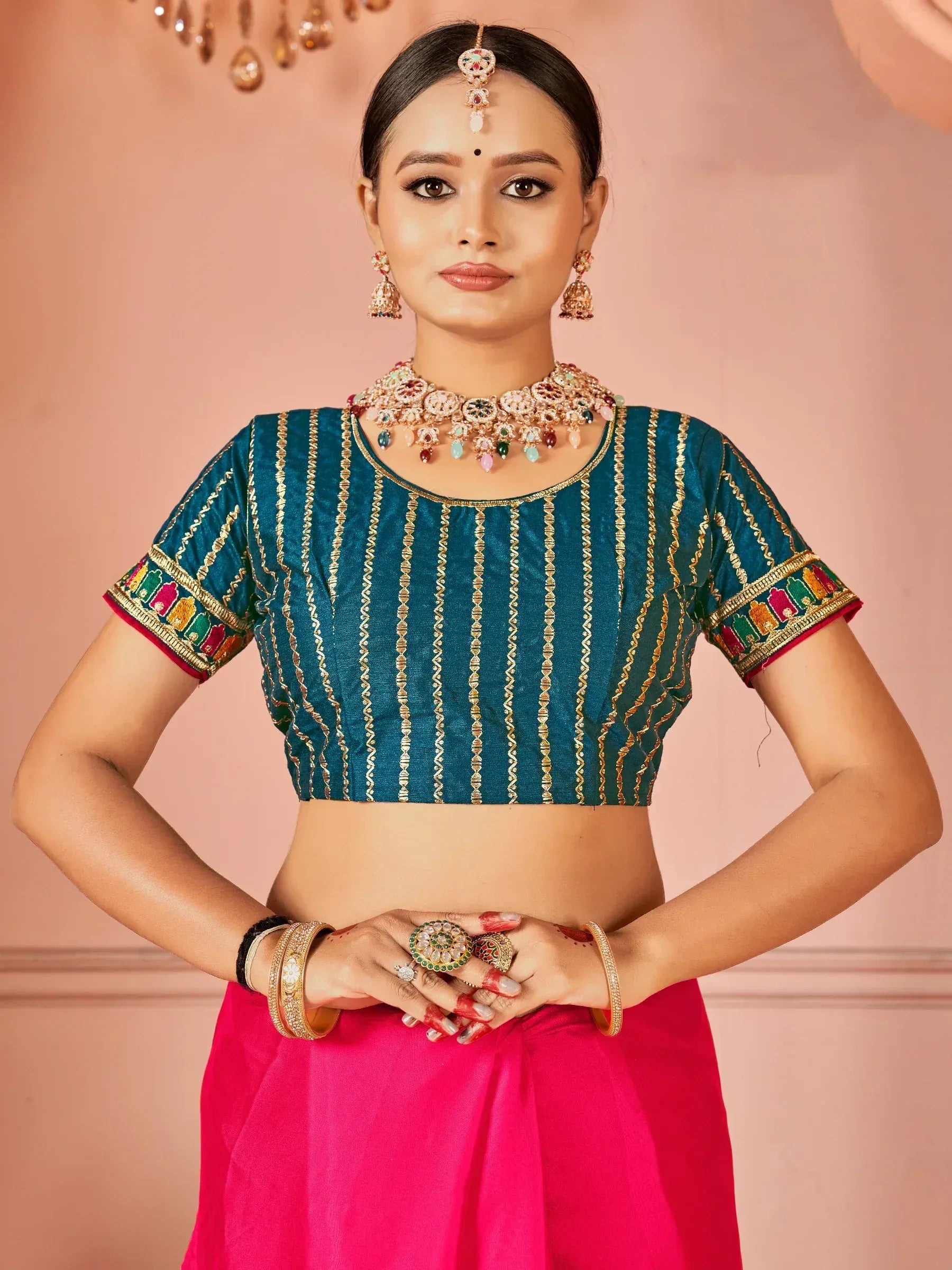 Teal embroidered blouse with gold stripes and colorful border, paired with pink lehenga, traditional Indian ethnic wear