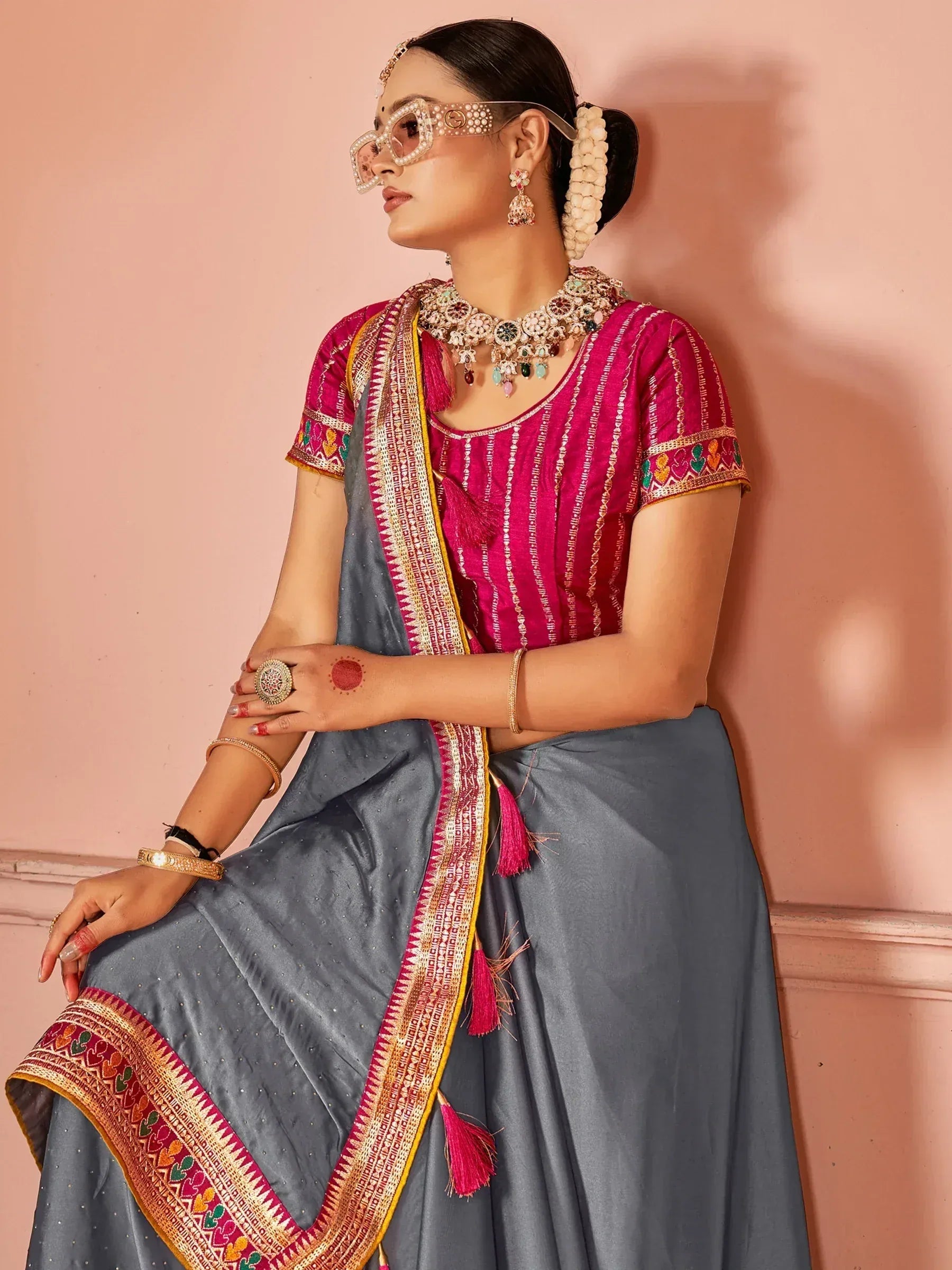 Woman in grey lehenga with pink embroidered blouse and traditional jewelry, styled for ethnic occasions