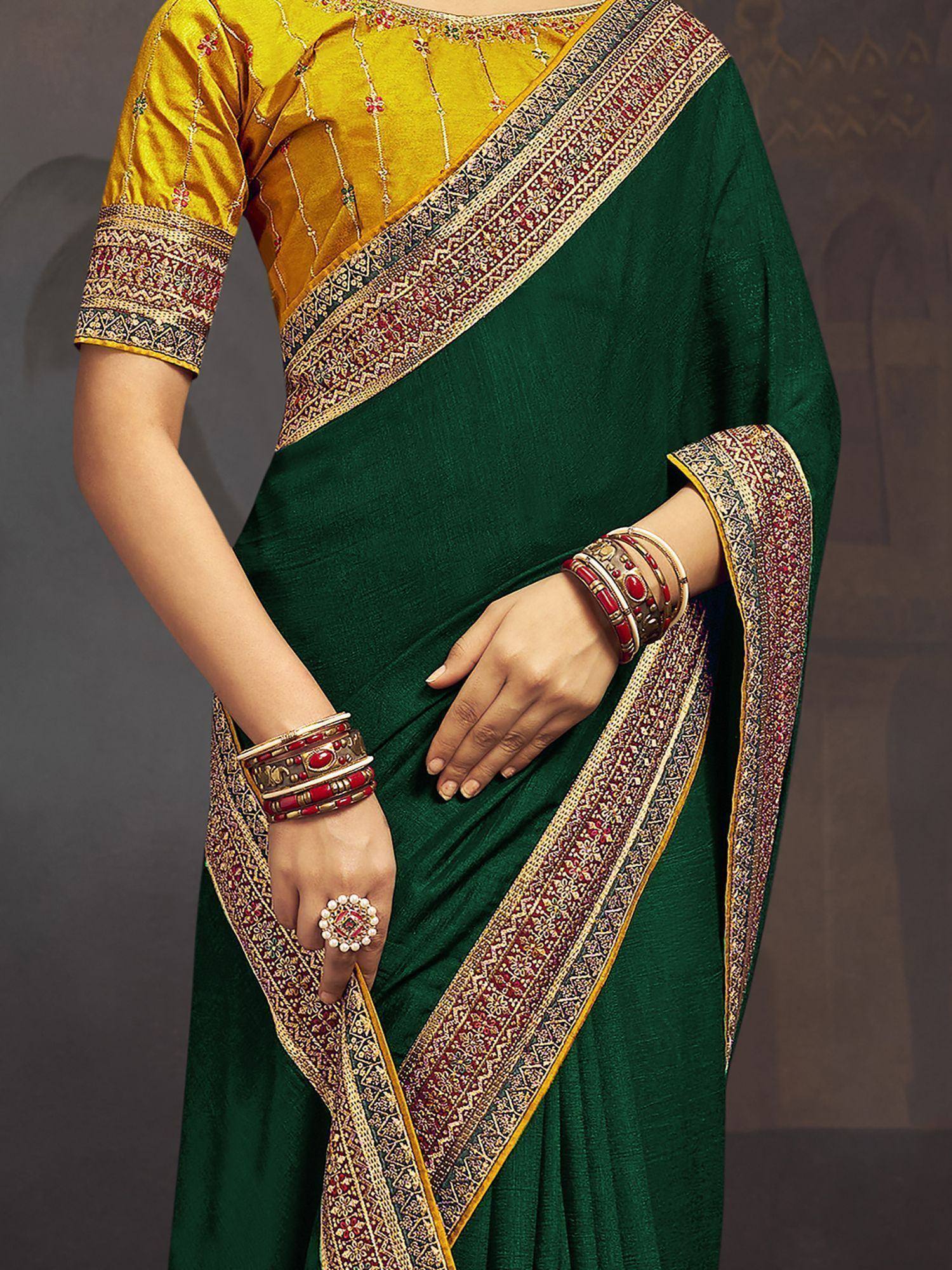 Emerald green saree with gold and red border, paired with yellow embroidered blouse and traditional bangles.