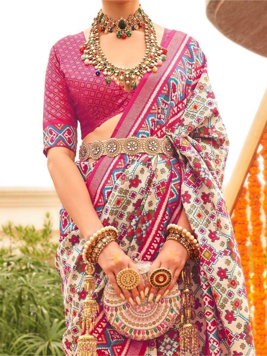 Woman in vibrant pink and cream printed saree with heavy jewelry, perfect for Indian ethnic occasions