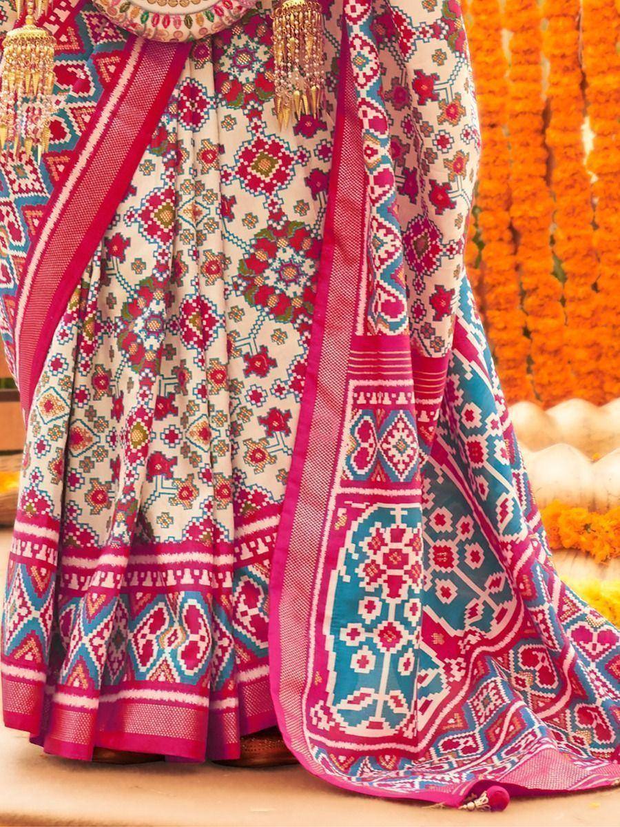 Vibrant ethnic lehenga choli with geometric floral print, pink border, and gold tassels, perfect for Indian festivals.