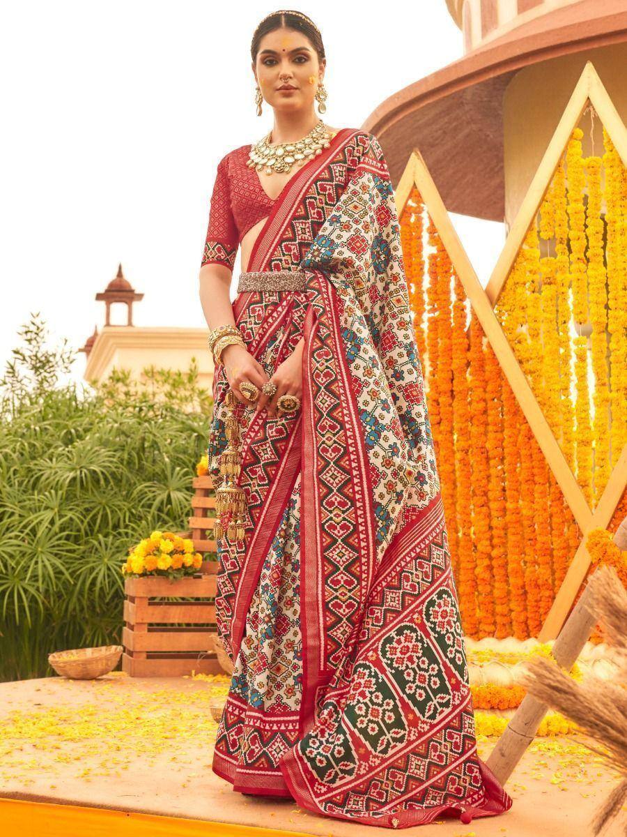 Woman in vibrant red and white printed saree with ethnic jewelry, festive marigold backdrop