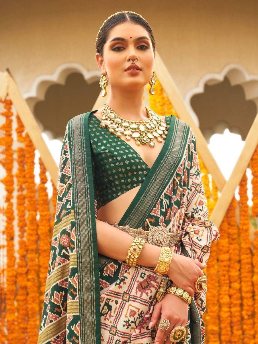 Green printed saree with blouse, traditional Indian jewelry, and floral backdrop