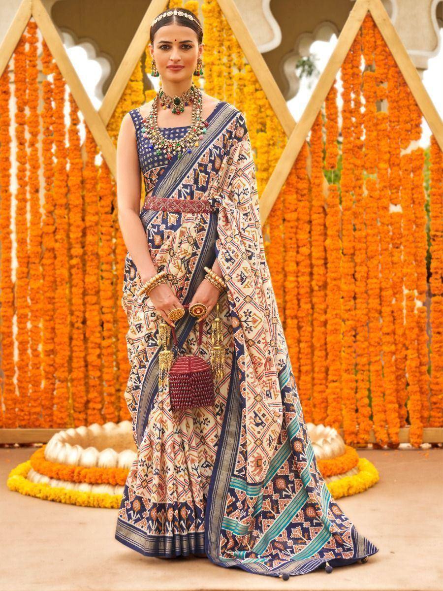 Woman in printed ethnic saree with jewelry, marigold backdrop, Indian festive wear