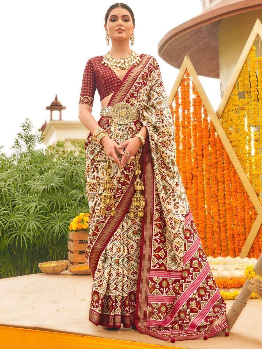 Elegant Indian saree with intricate geometric print, maroon blouse, and gold jewelry for festive occasions