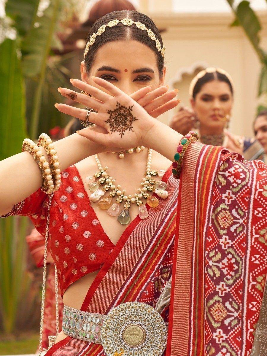 Red ethnic saree with gold embroidery, henna hand design, and traditional jewelry for Indian weddings