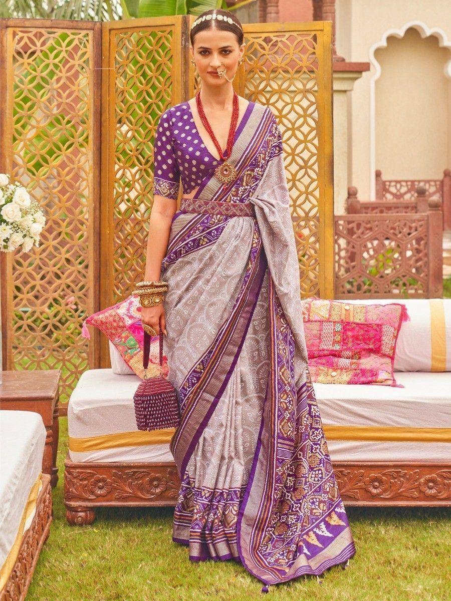 Woman in purple and silver designer saree with ethnic jewelry, perfect for Indian weddings or festive occasions