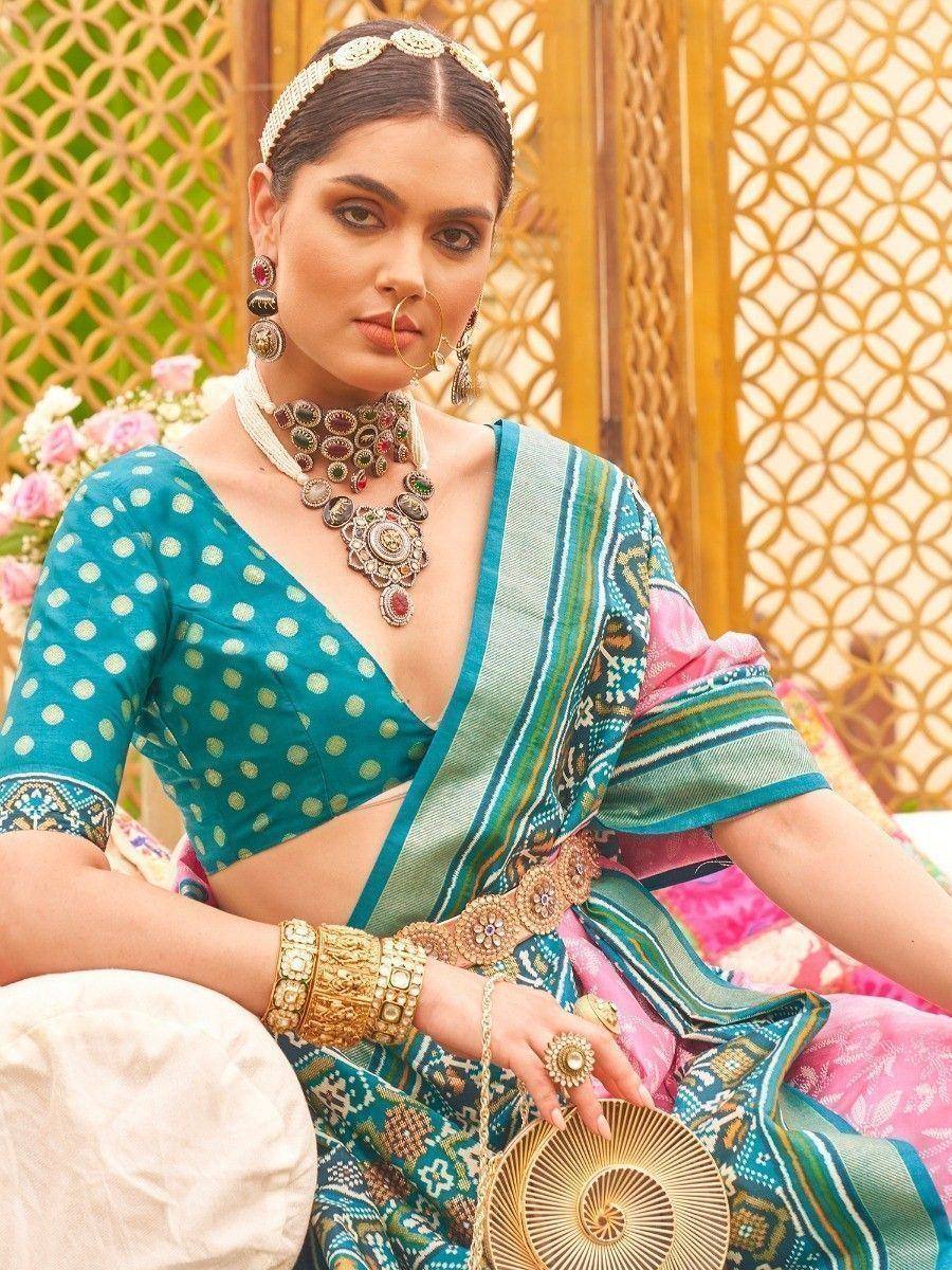 Woman in teal polka dot blouse and patterned saree with gold jewelry, traditional Indian ethnic wear
