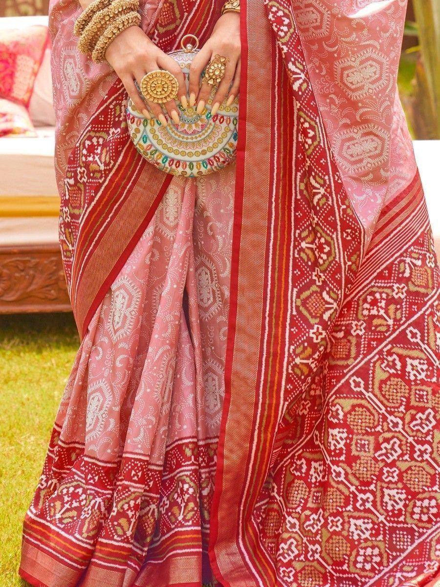 Pink and red printed saree with gold jewelry and embroidered clutch, perfect for Indian ethnic occasions