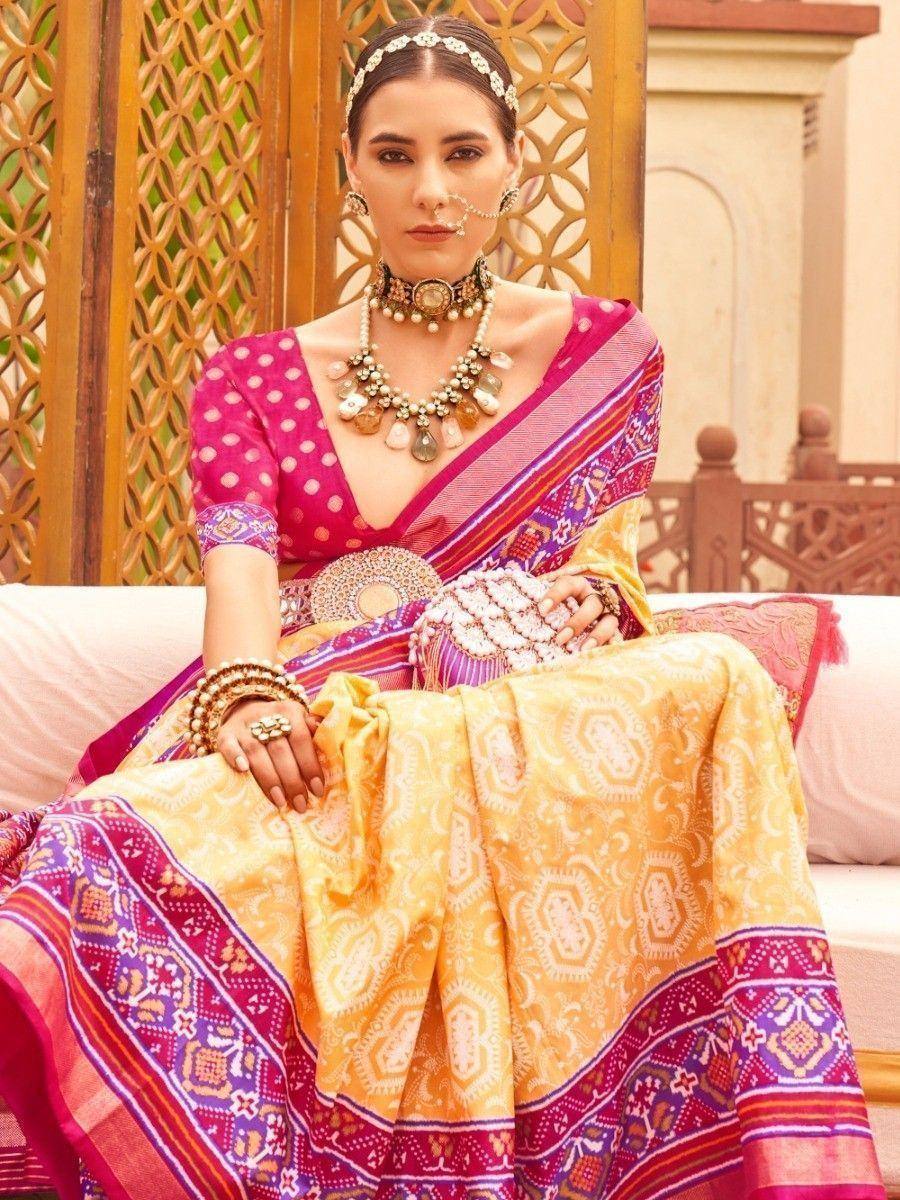 Elegant Indian ethnic wear with vibrant pink and yellow saree, traditional jewelry, and ornate patterns.