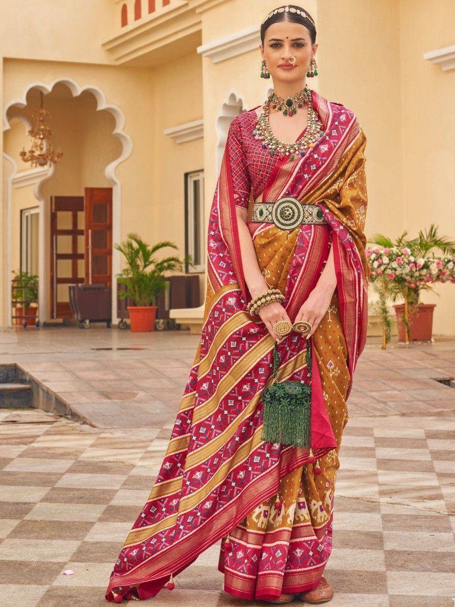 Woman in traditional Indian saree with red and gold patterns, ethnic jewelry, and temple backdrop