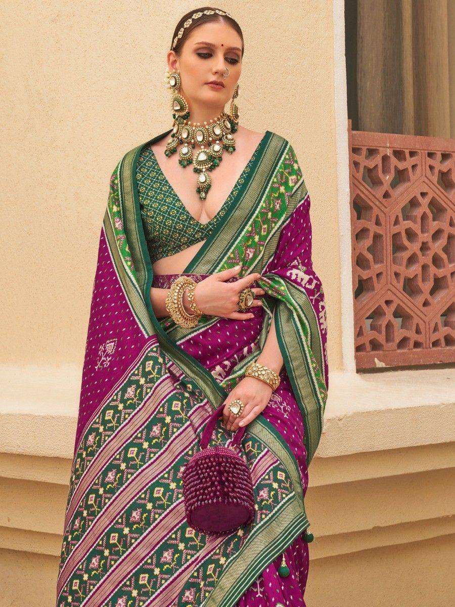 Purple and green ethnic saree with intricate patterns, paired with traditional jewelry and a matching clutch.