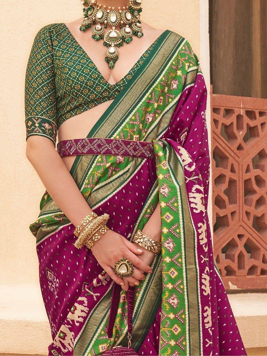 Purple and green ethnic saree with printed blouse, traditional jewelry, and intricate border design