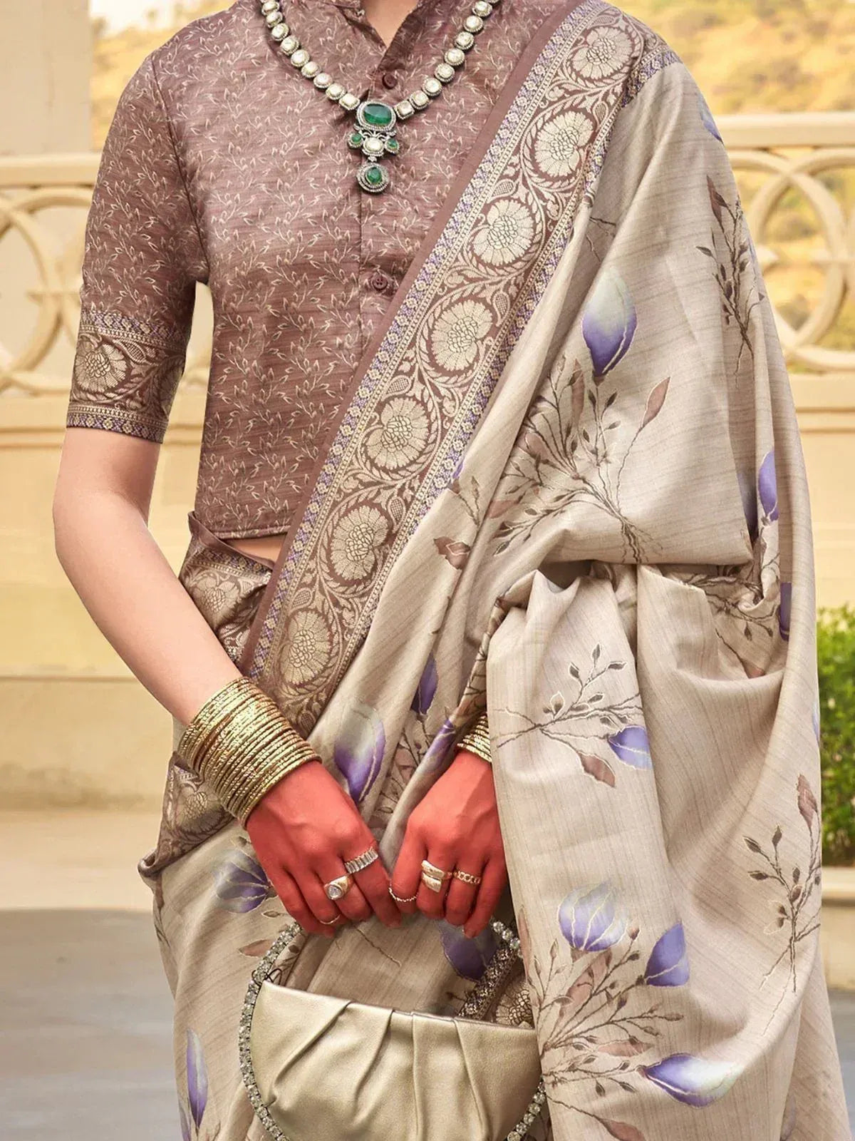 Elegant beige saree with purple floral print, paired with brown blouse and traditional jewelry