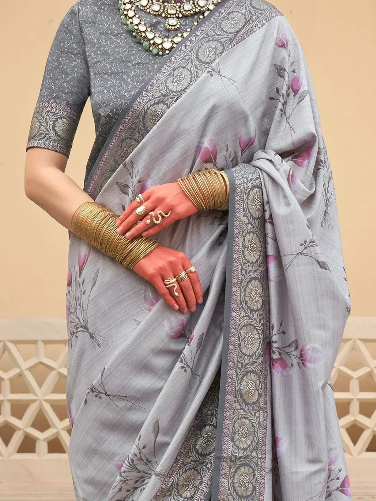 Grey floral saree with intricate border, paired with ethnic jewelry and bangles, perfect for Indian occasions